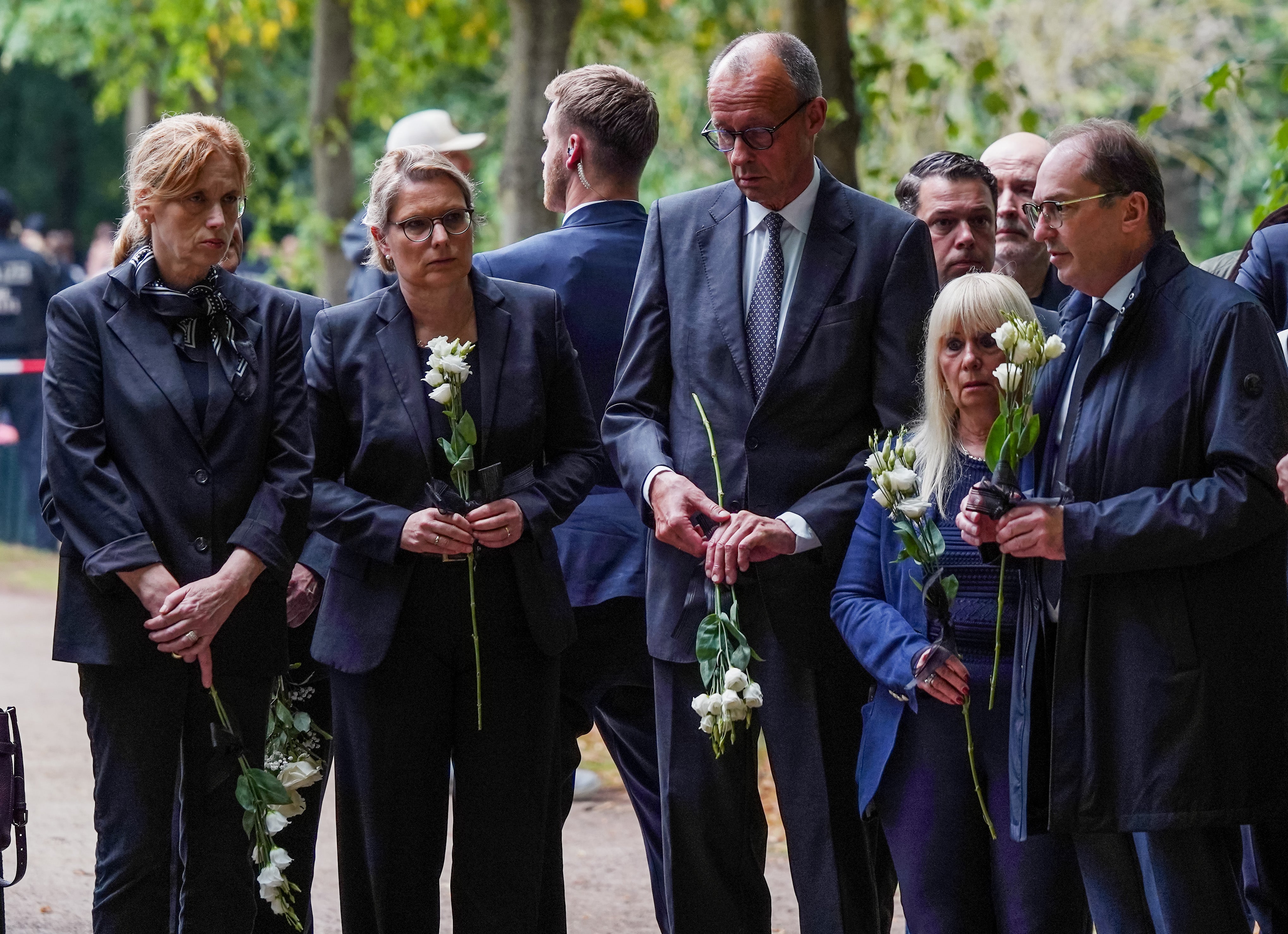 German Chancellor Friedrich Merz (C), Interior Minister Alexander Dobrindt (R), Justice Minister Stefanie Hubig (2L) and Family Minister Karin Prien (L) carry flowers as they visit the crime scene at Tiergarten (Getty)