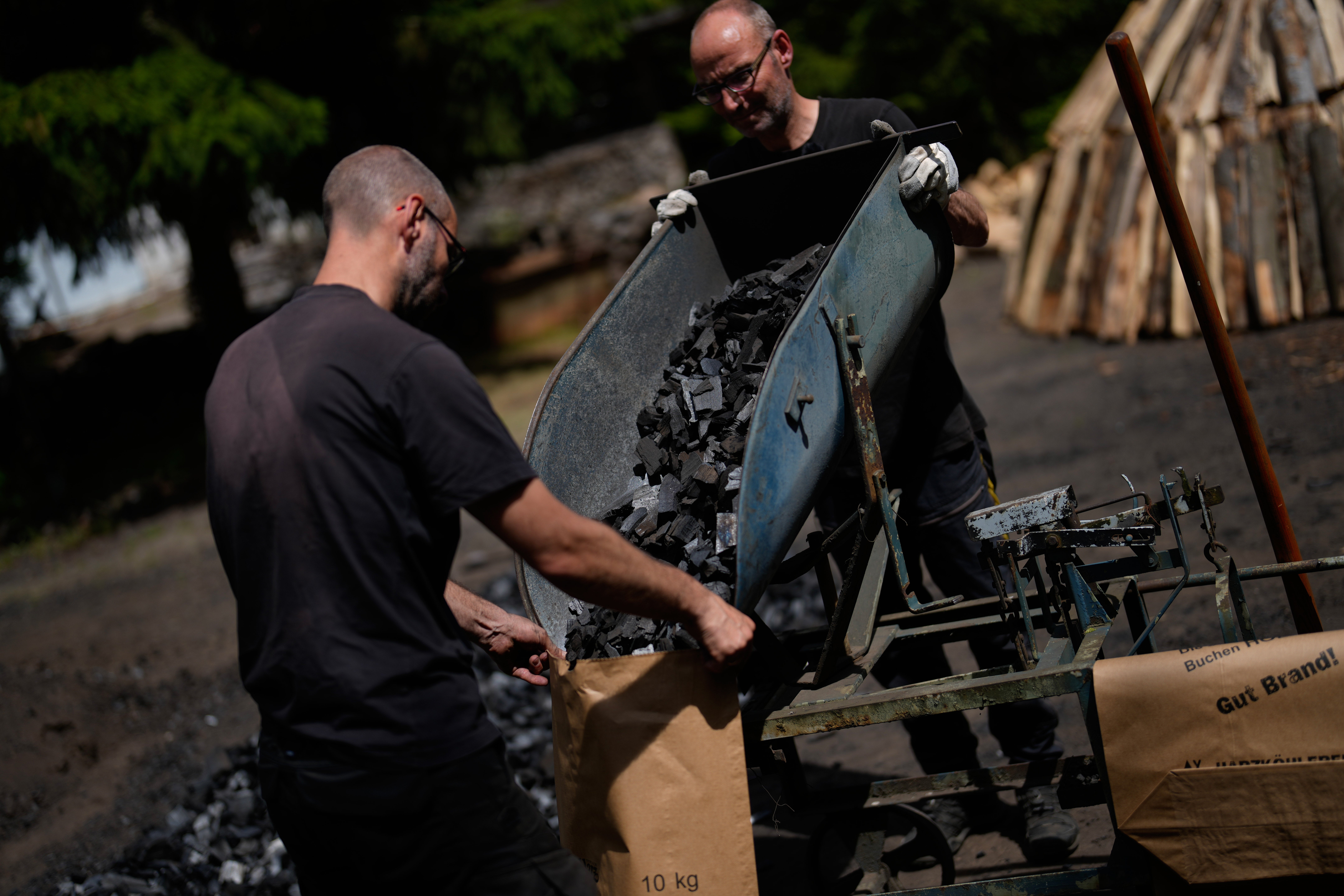 Brothers Immo and Sascha Feldmer put charcoal into paper bags after weighing it at their traditional production site