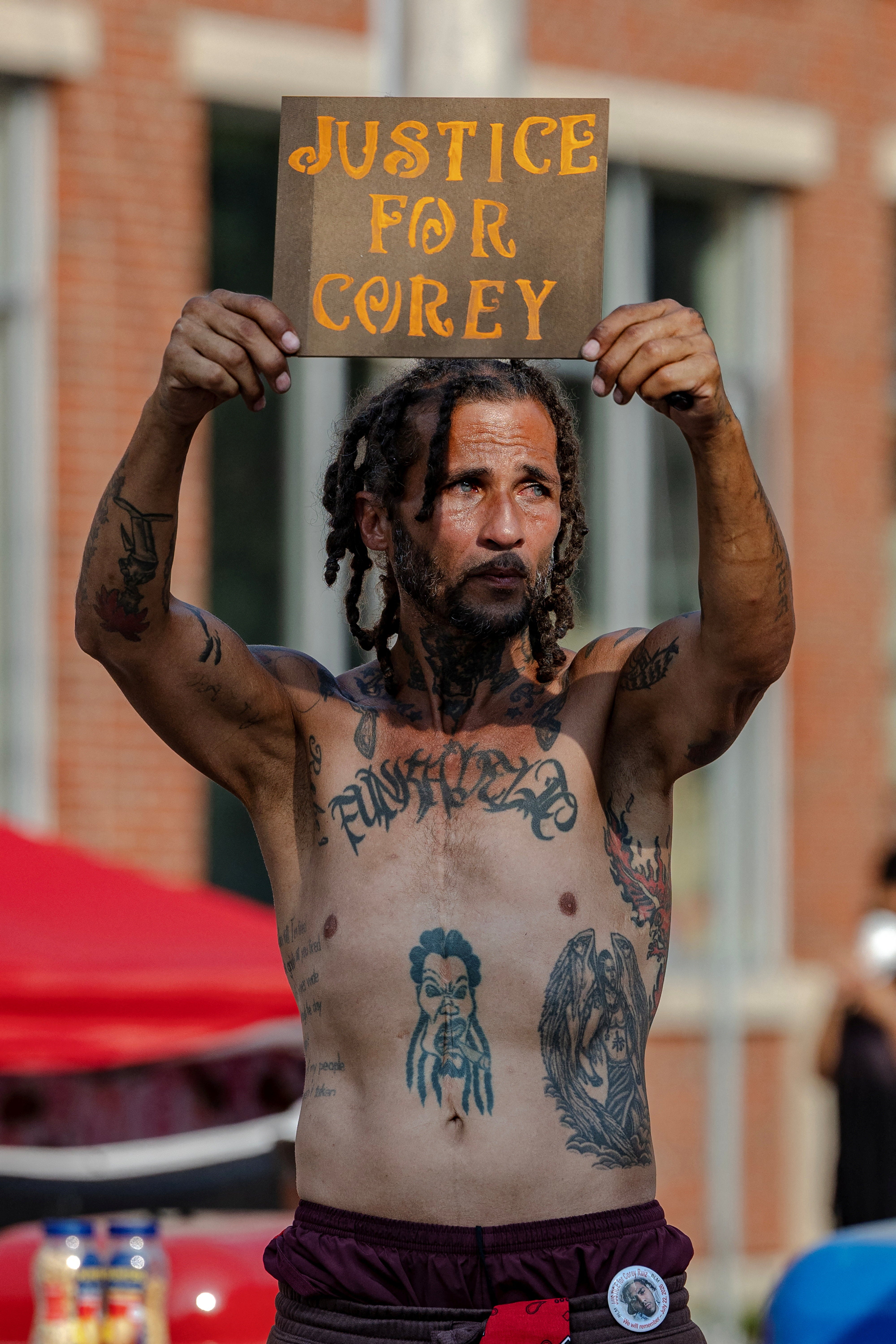 A mourner holds up a sign at a memorial for Corey Ruiz at the site where he was shot and killed by police on July 22, in Madison