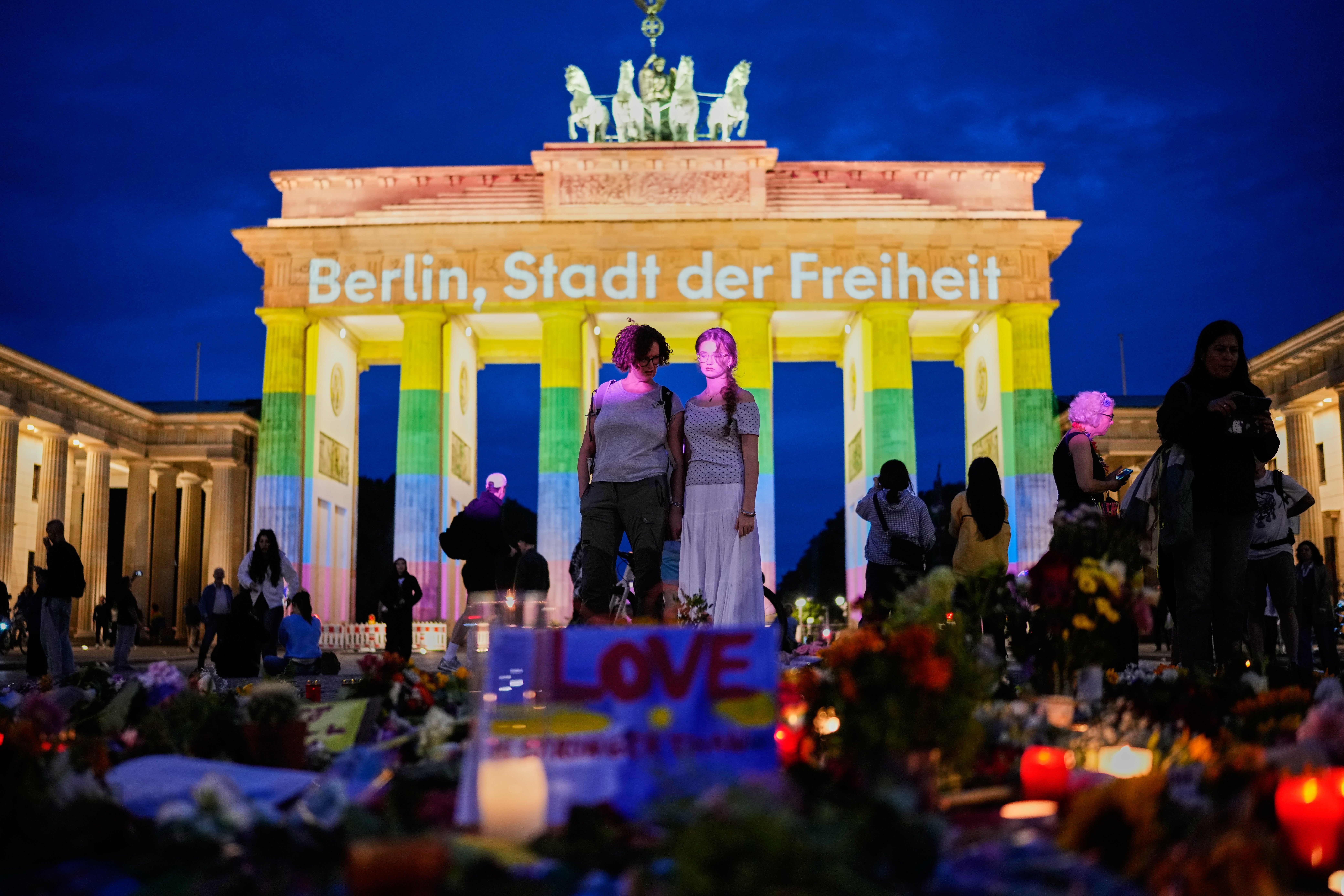 People gather in front of the Brandenburg Gate illuminated with the message "Berlin, city of freedom", commemorating the victims of the Pride attack