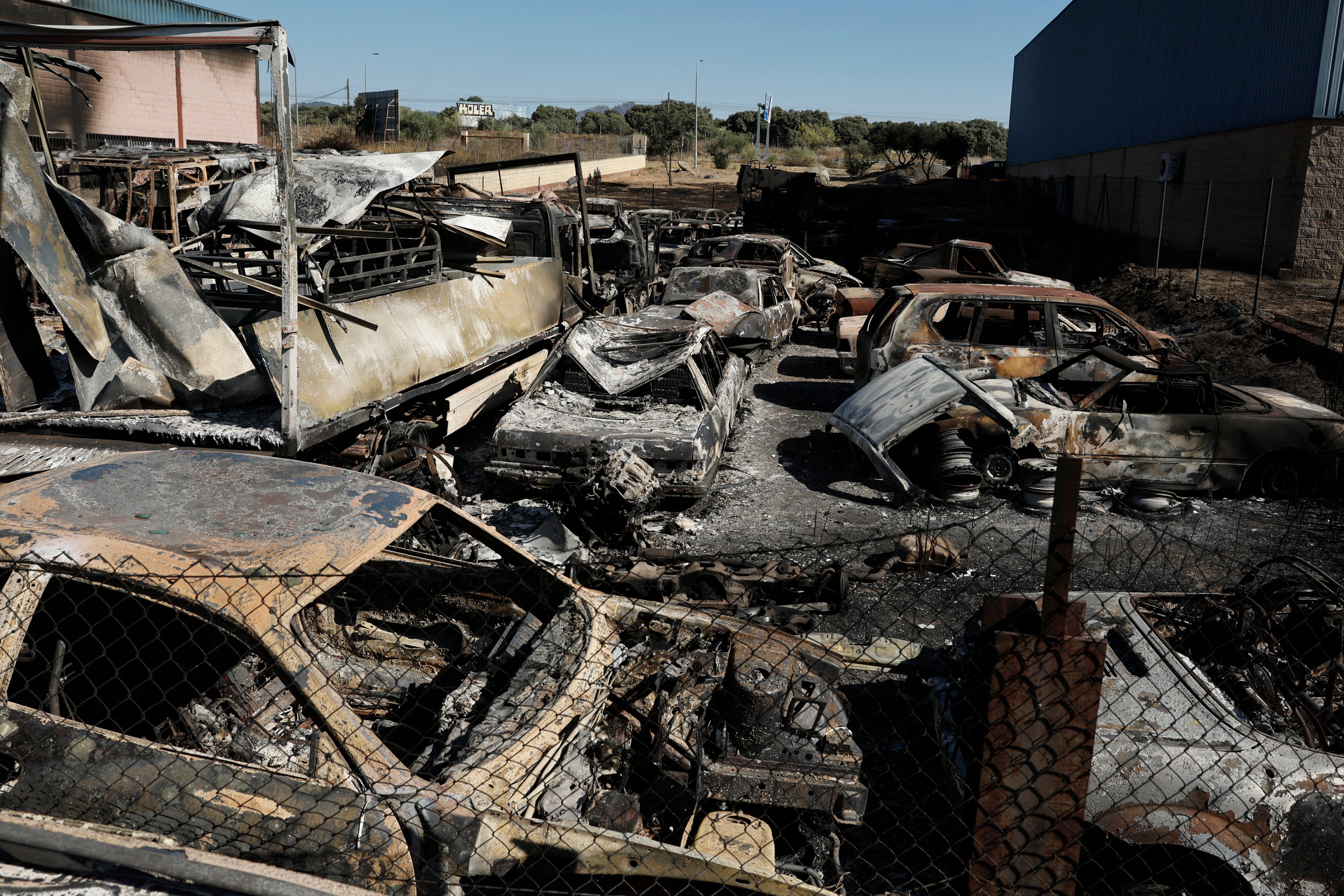 Burnt-out vehicles are seen in an industrial estate following a wildfire in Chapineria, Spain