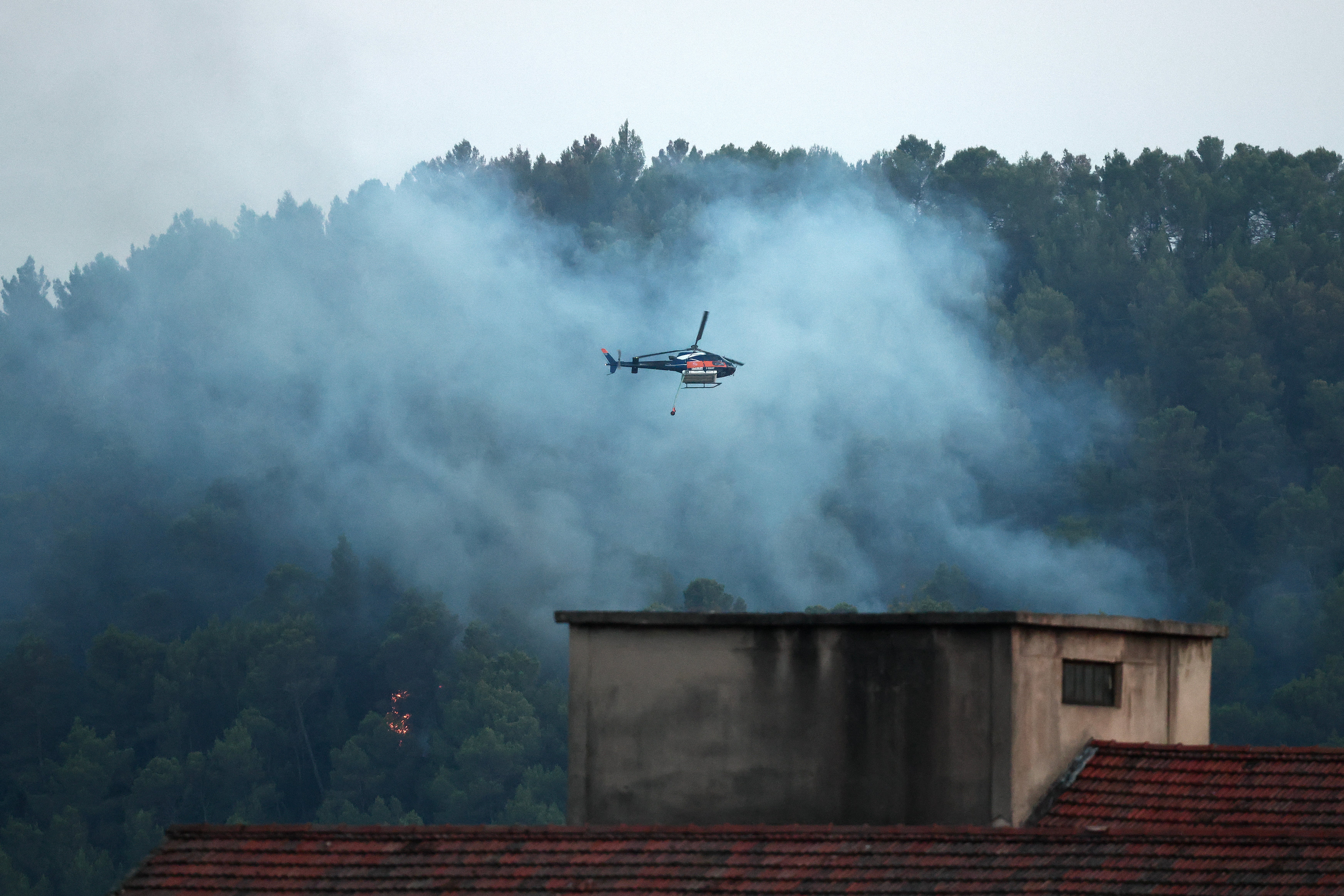 Water-bombing helicopter, Airbus Helicopter H125, drops water over a burning area during a wildfire in front of Barjols, southeastern France (AFP/Getty)