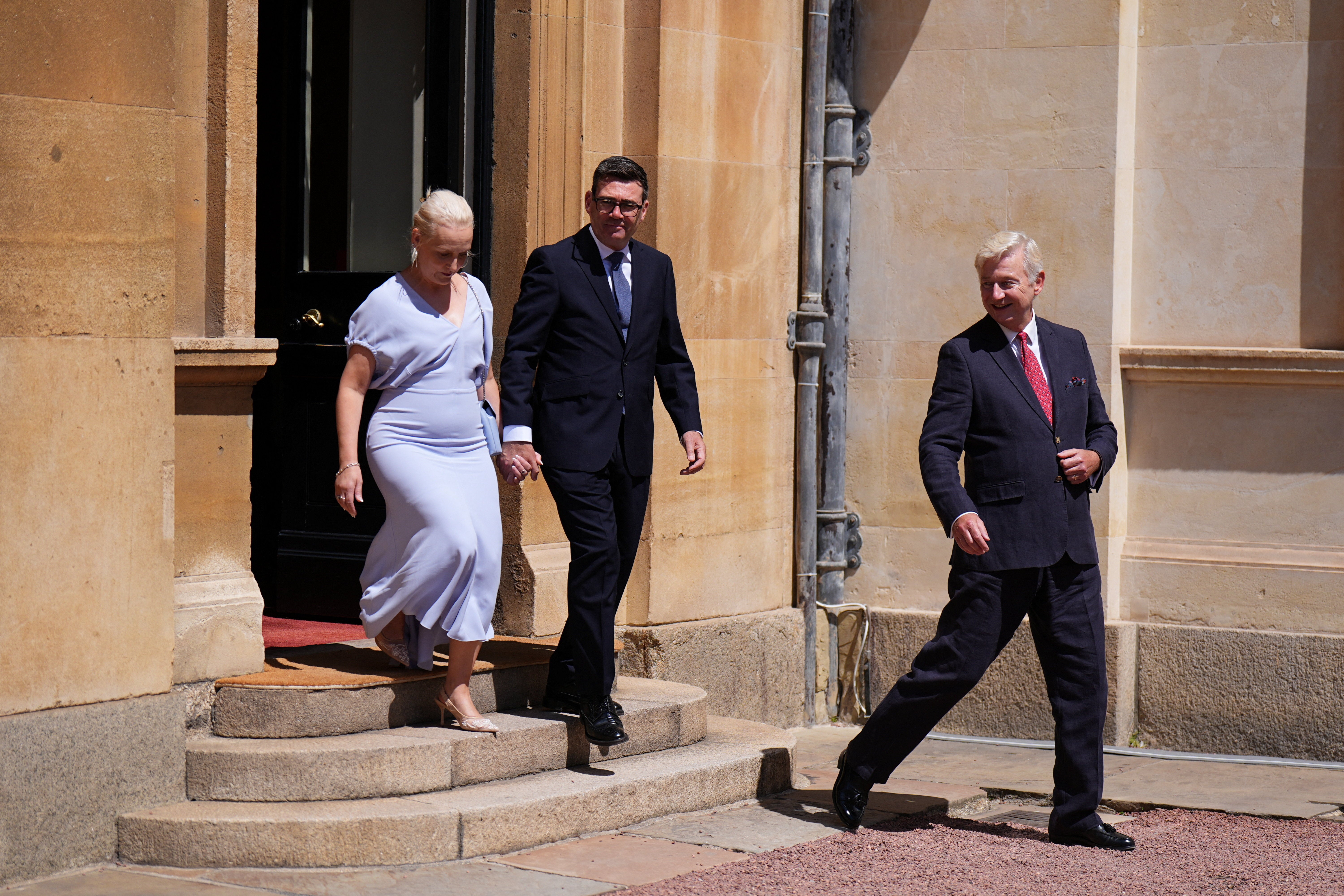 Sir Clive Alderton, right, leaves Buckingham Palace with newly appointed Prime Minister Andy Burnham and his wife Marie-France van Heel on 20 July (Reuters)
