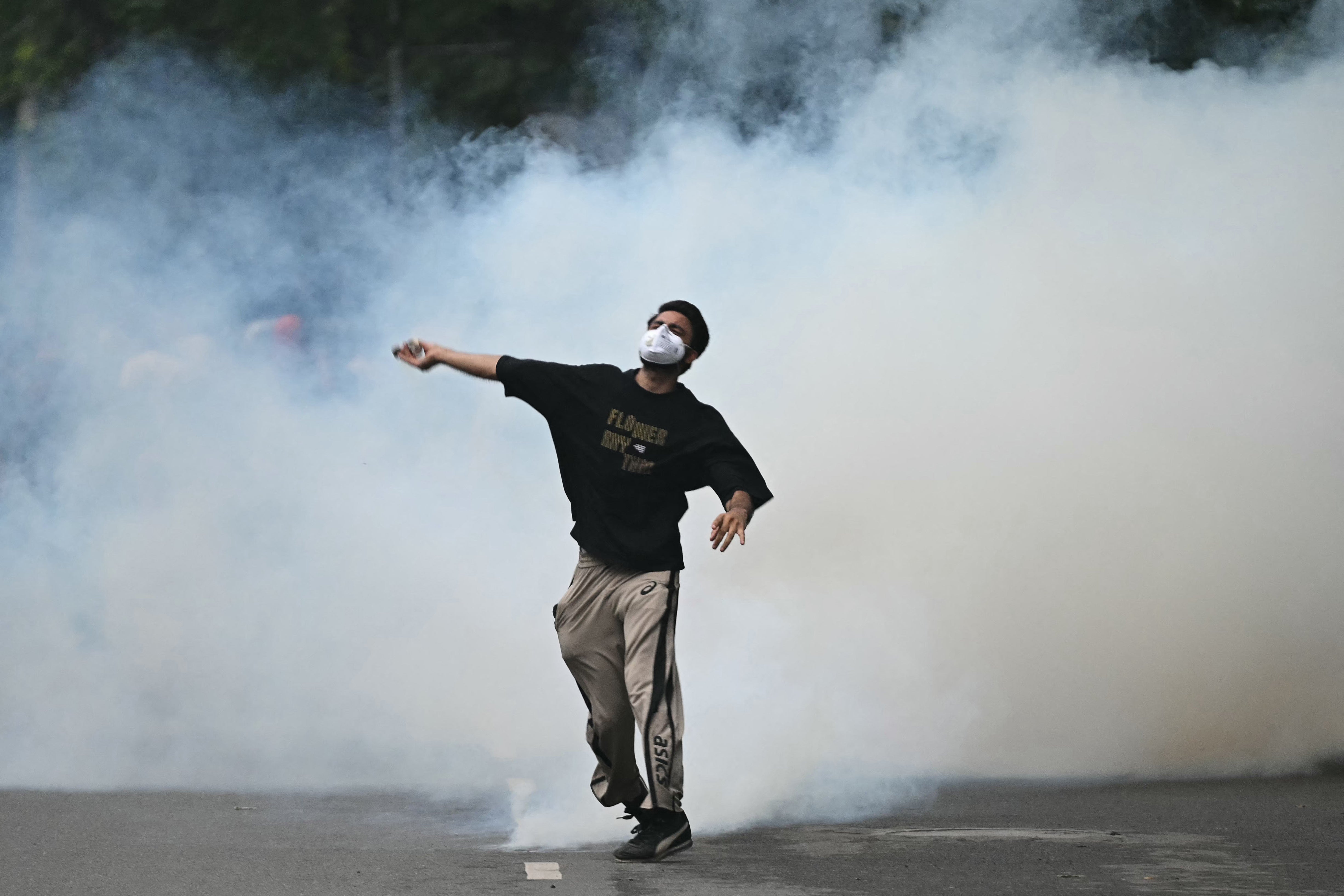 A protester throws back a tear gas canister fired by Rapid Action Force (RAF) personnel to disperse supporters of the Cockroach Janta Party (AFP/Getty)