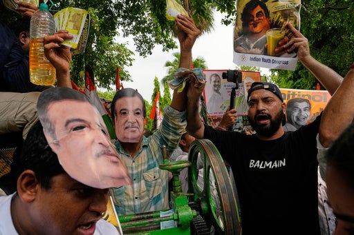 Members of the Indian Youth Congress wearing masks depicting India's Minister of Road Transport and Highways Nitin Gadkari shout anti-government slogans while holding mock currency notes during a protest against the government's mandatory rollout of E20 fuel