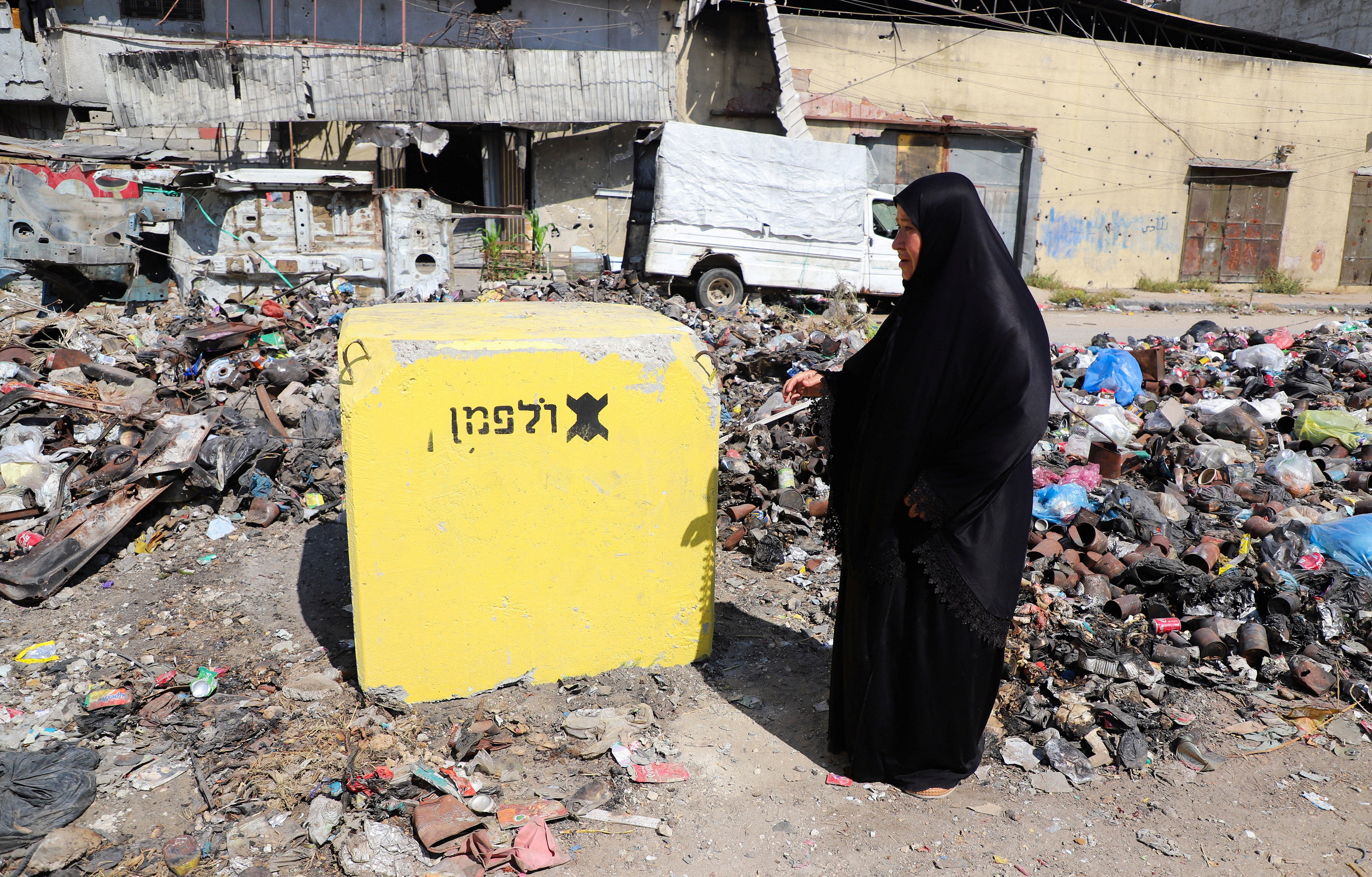 A Palestinian woman looks at a yellow concrete block marking the 'yellow zone' under Israeli military control, in Tufah neighborhood, in Gaza City, July 27, 2026. REUTERS/Ebrahim Hajjaj