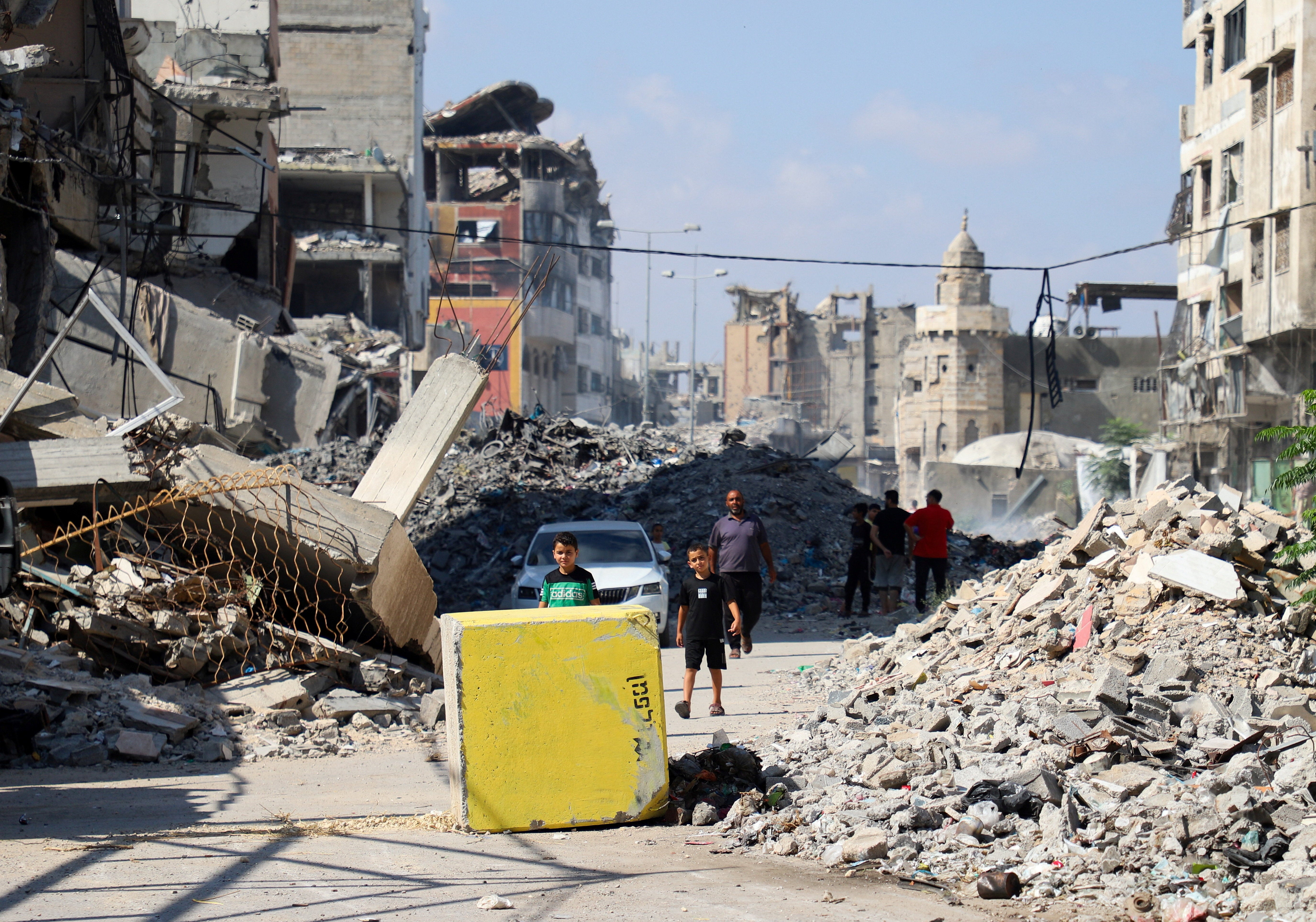 Palestinians look towards a yellow concrete block marking the 'yellow zone' under Israeli military control, in Tufah neighborhood, in Gaza City, July 27, 2026