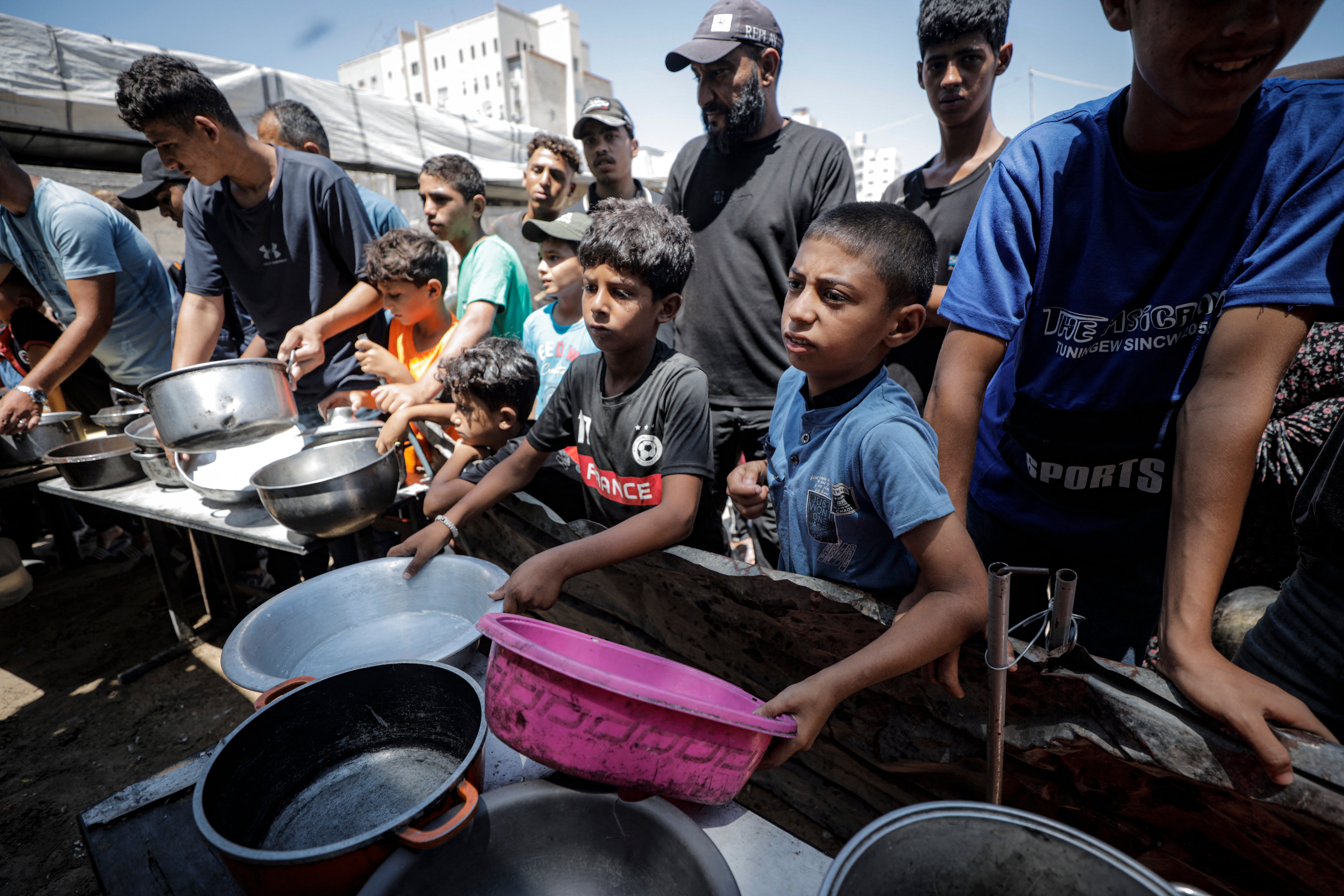 Displaced Palestinians hold empty pots and containers to receive food supplies in Gaza City, Gaza Strip, on July 27, 2026. Widespread displacement and the ongoing conflict have severely disrupted access to essential resources, leaving many families reliant on communal relief efforts for their daily meals (AFP/Getty)