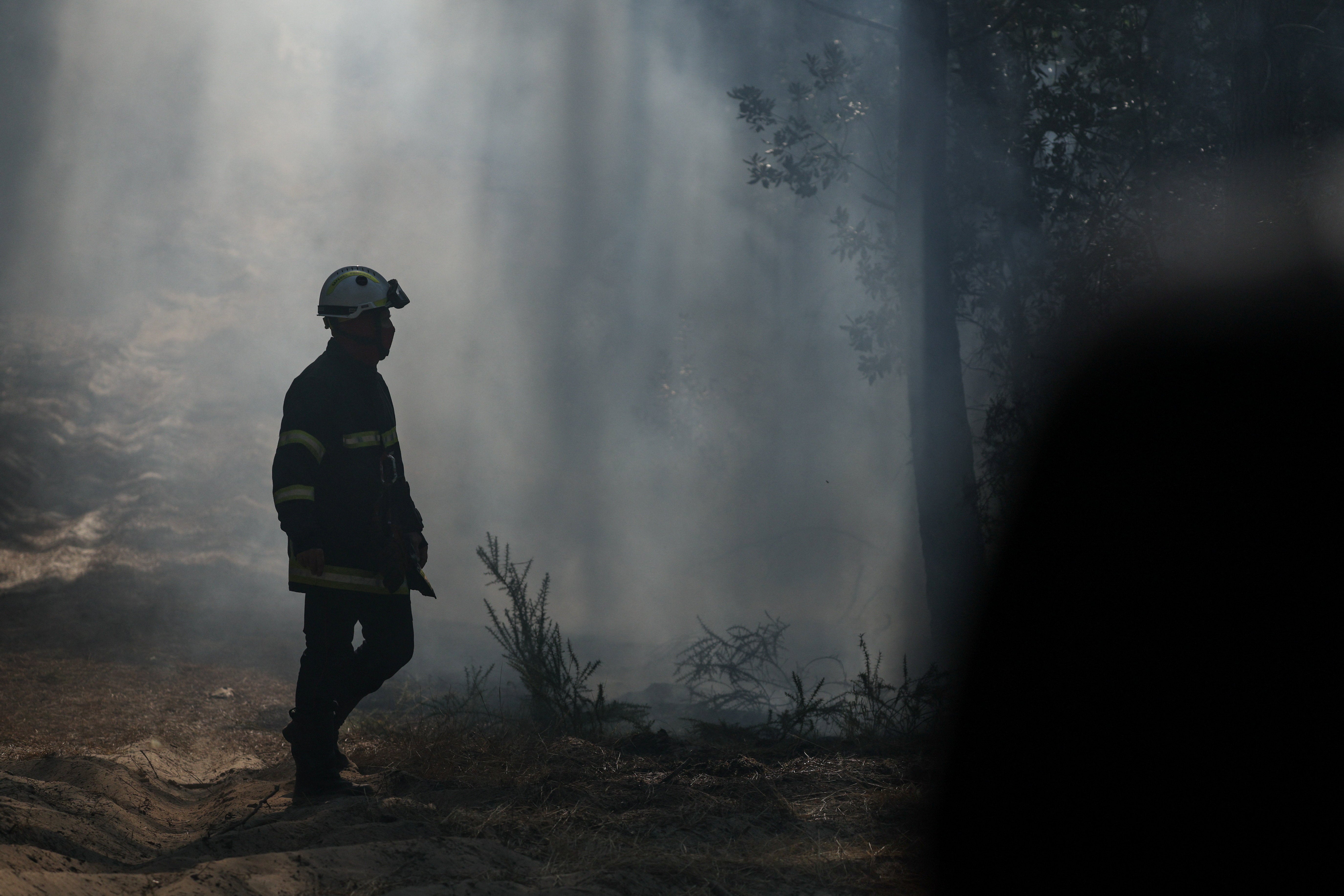 A firefighter amid smoke rising from hotspots at Le Grand Crohot