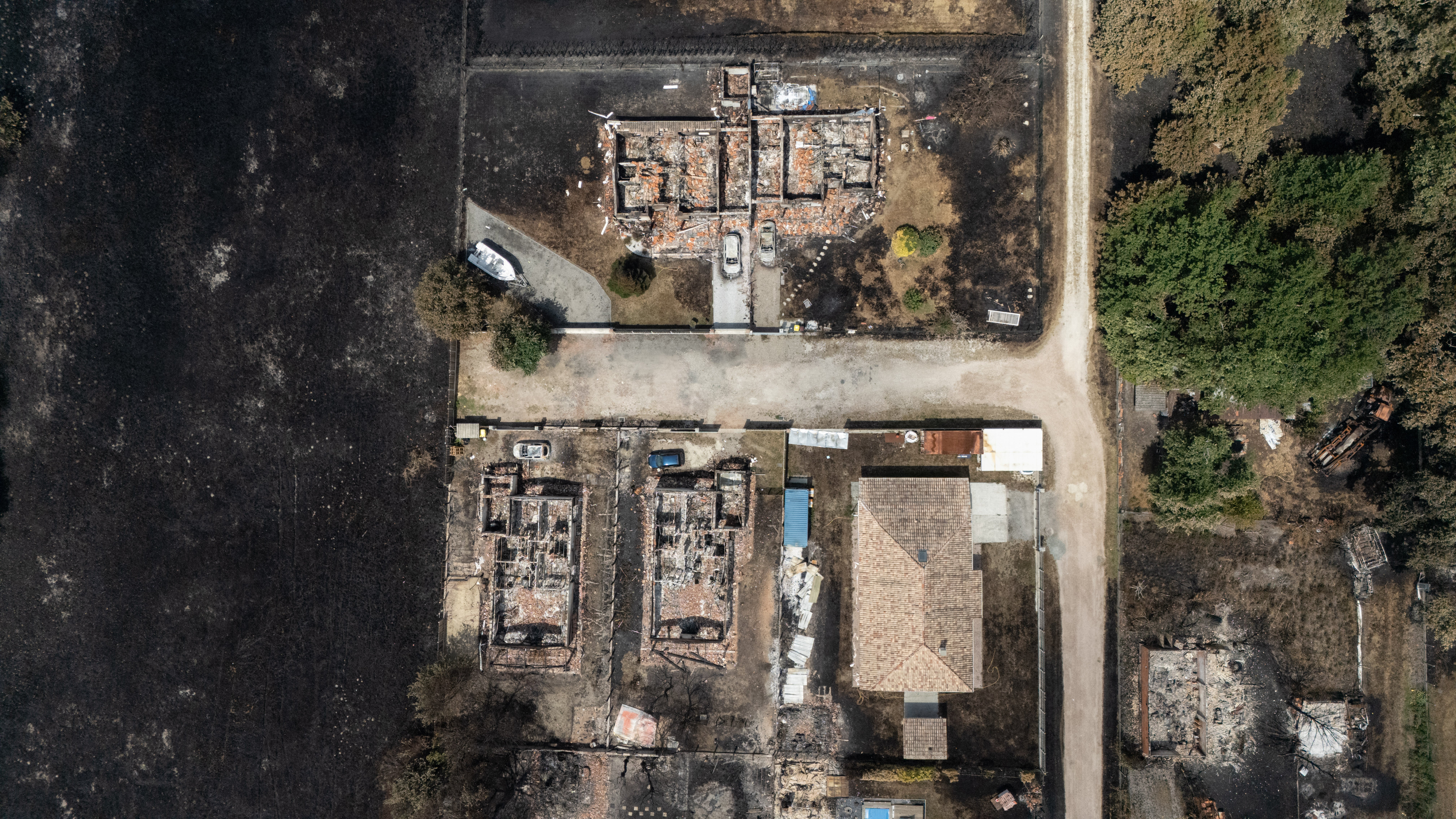 This aerial view shows damaged houses in a burnt area in the town of Le Porge, following a wildfire in the Gironde Department, southwestern France, on 27 July 2026