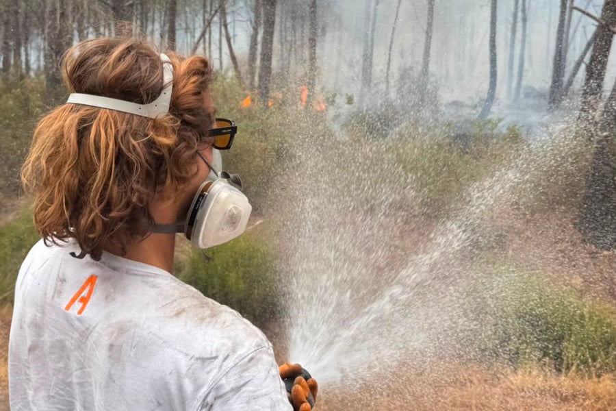 A woman in a mask sprays water at a forest fire in Lacanau, west of Bordeau (Mathias Monseigne)