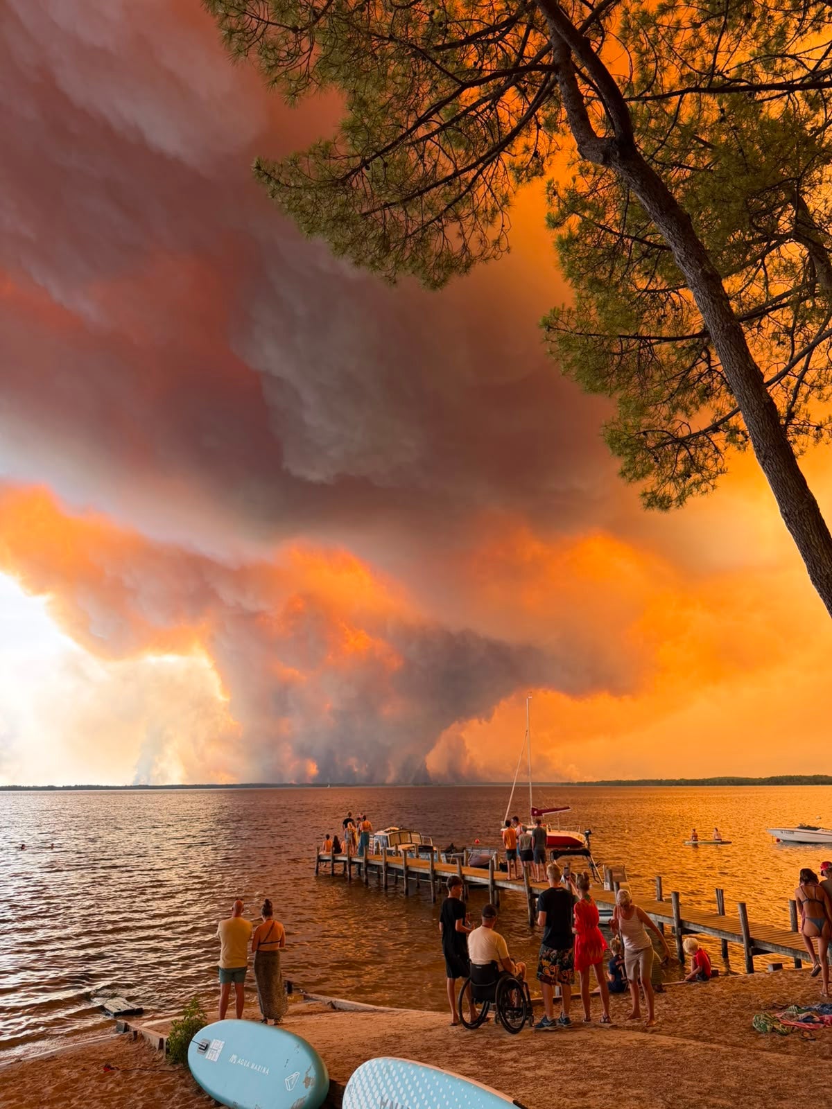 Nuvens de fogo encheram o céu, vistas por pessoas numa praia em Lacanau, perto de Bordéus