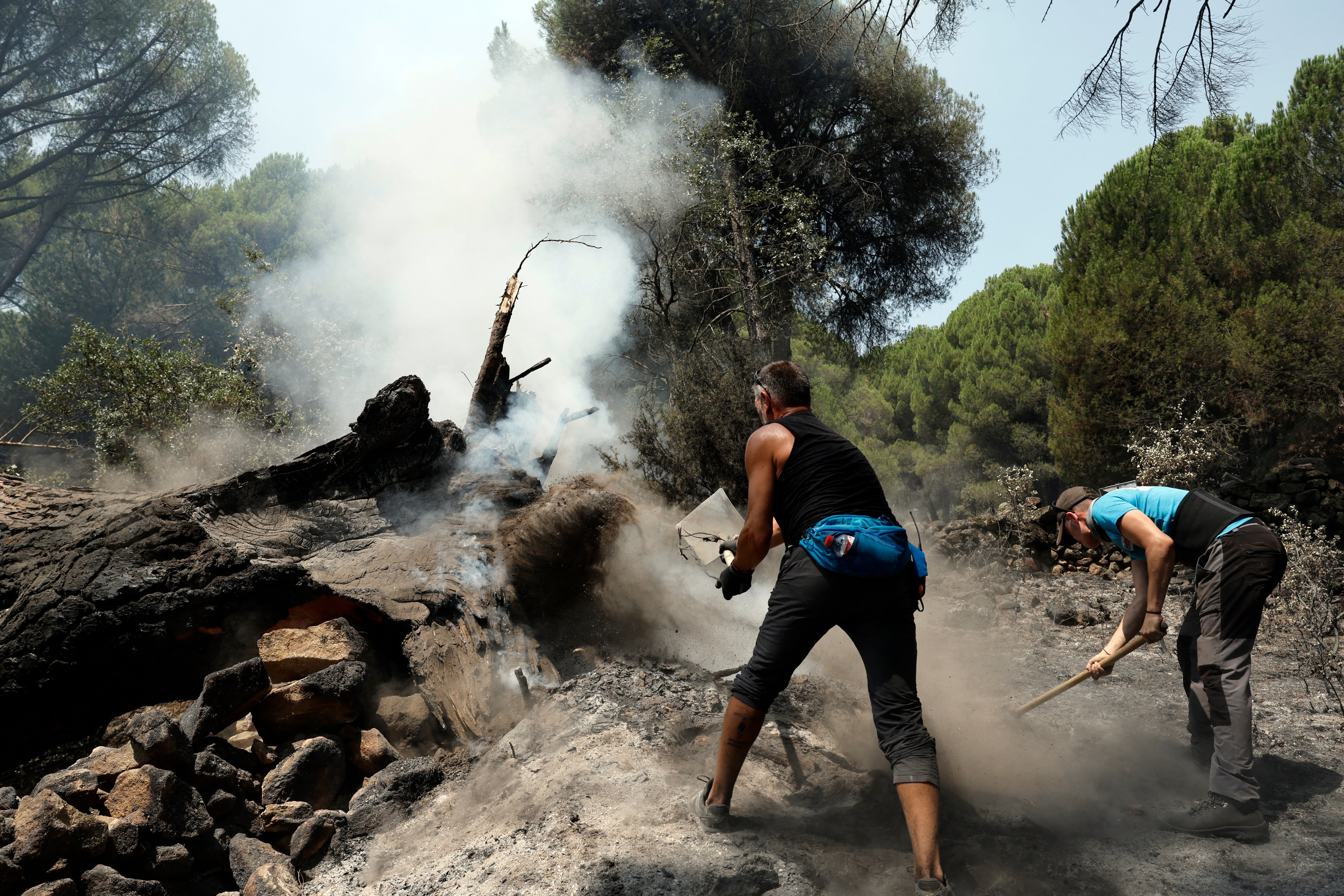 Residents smother embers with dirt to prevent reignition after a fire was brought under control near La Adrada, west of Madrid (AFP/Getty)