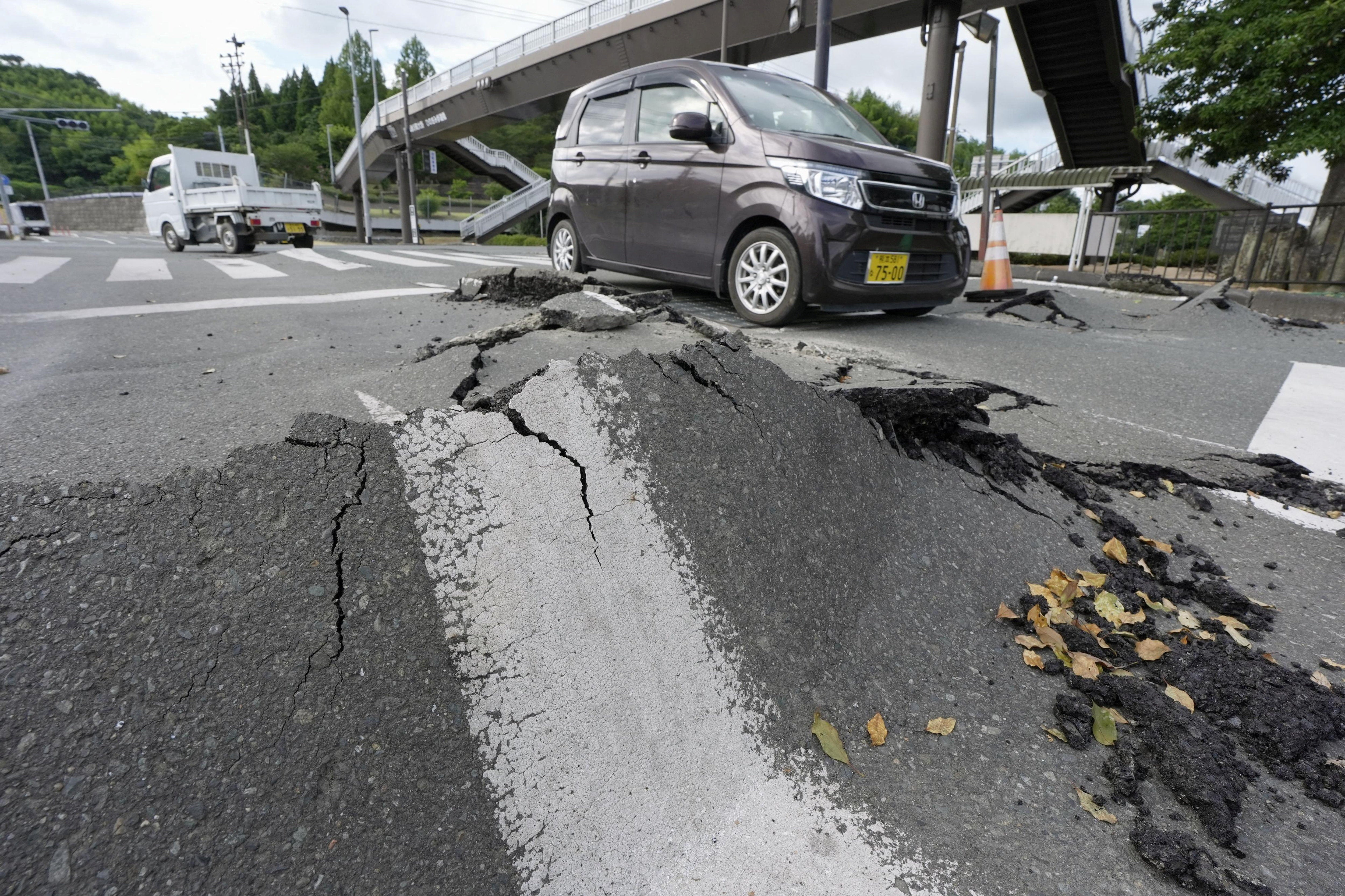 Vehicles pass a damaged road after an earthquake with a magnitude of 7.1 struck Japan's southern Kumamoto prefecture, in Hikawa town (Reuters)