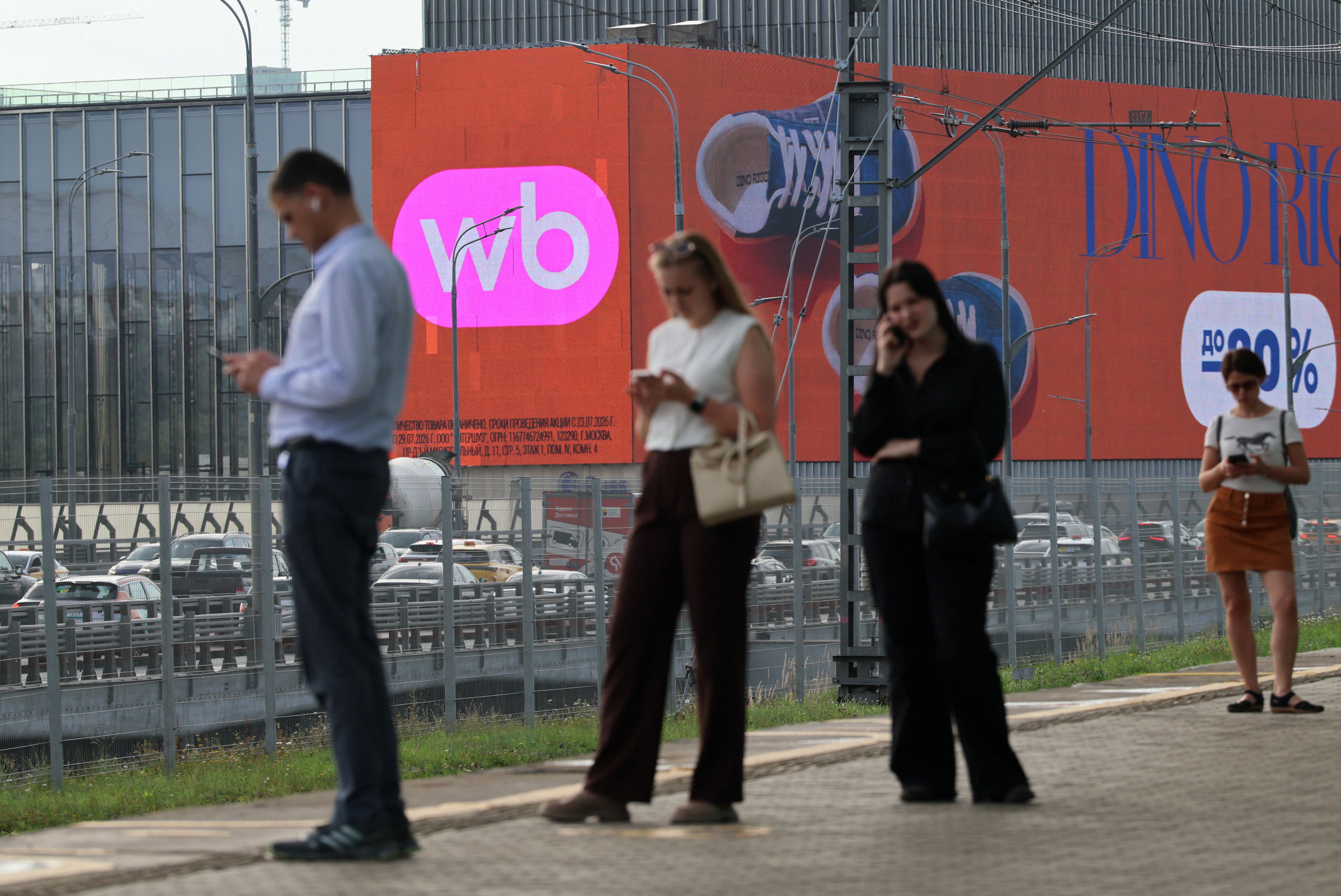 Pessoas esperam por um trem perto de uma tela que anuncia o varejista on-line Wildberries em Moscou, Rússia, 28 de julho de 2026