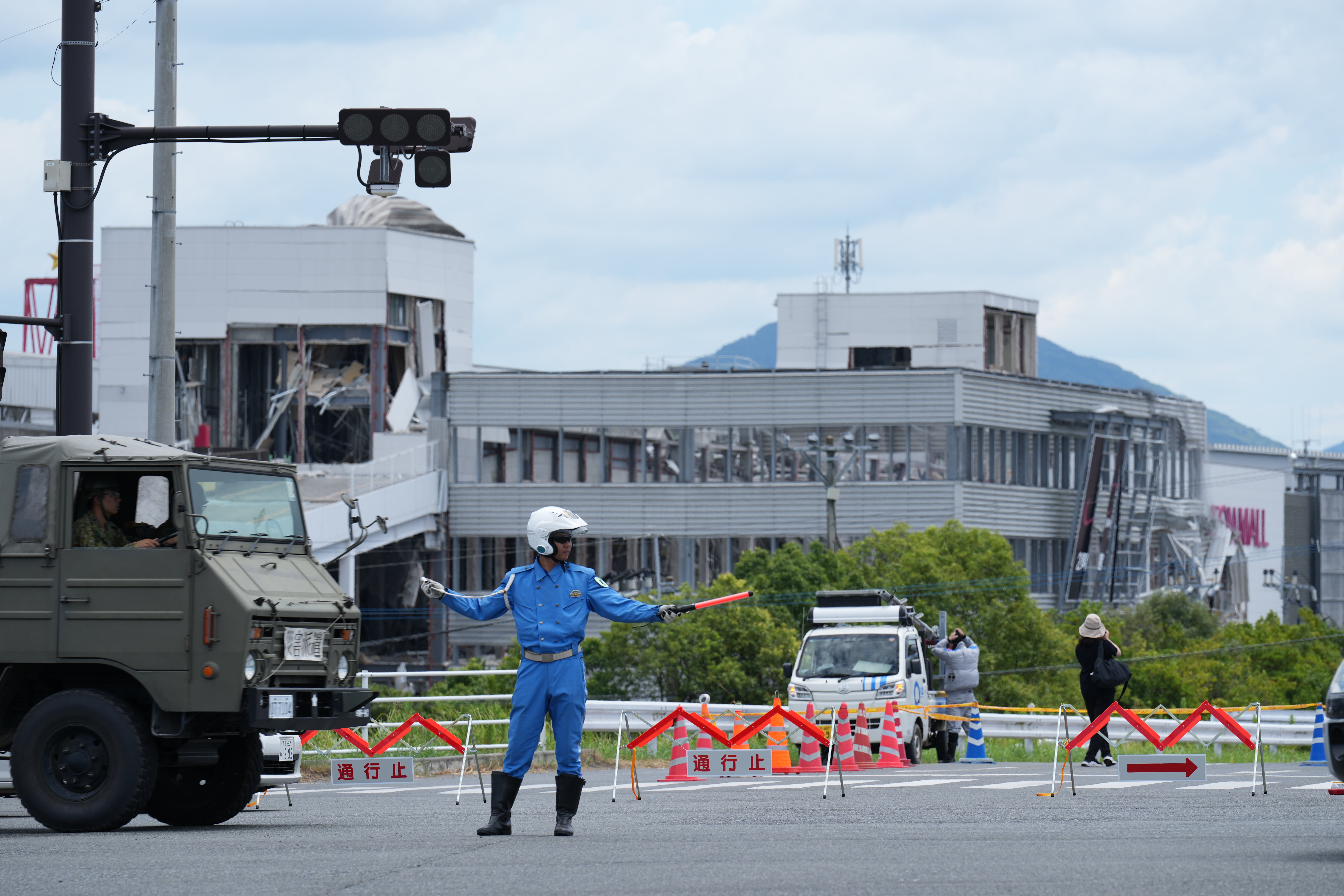 A police officer controls the traffic near AEON Mall, which was destroyed by an explosion following an earthquake, in Kashima, Kumamoto Prefecture (AP)