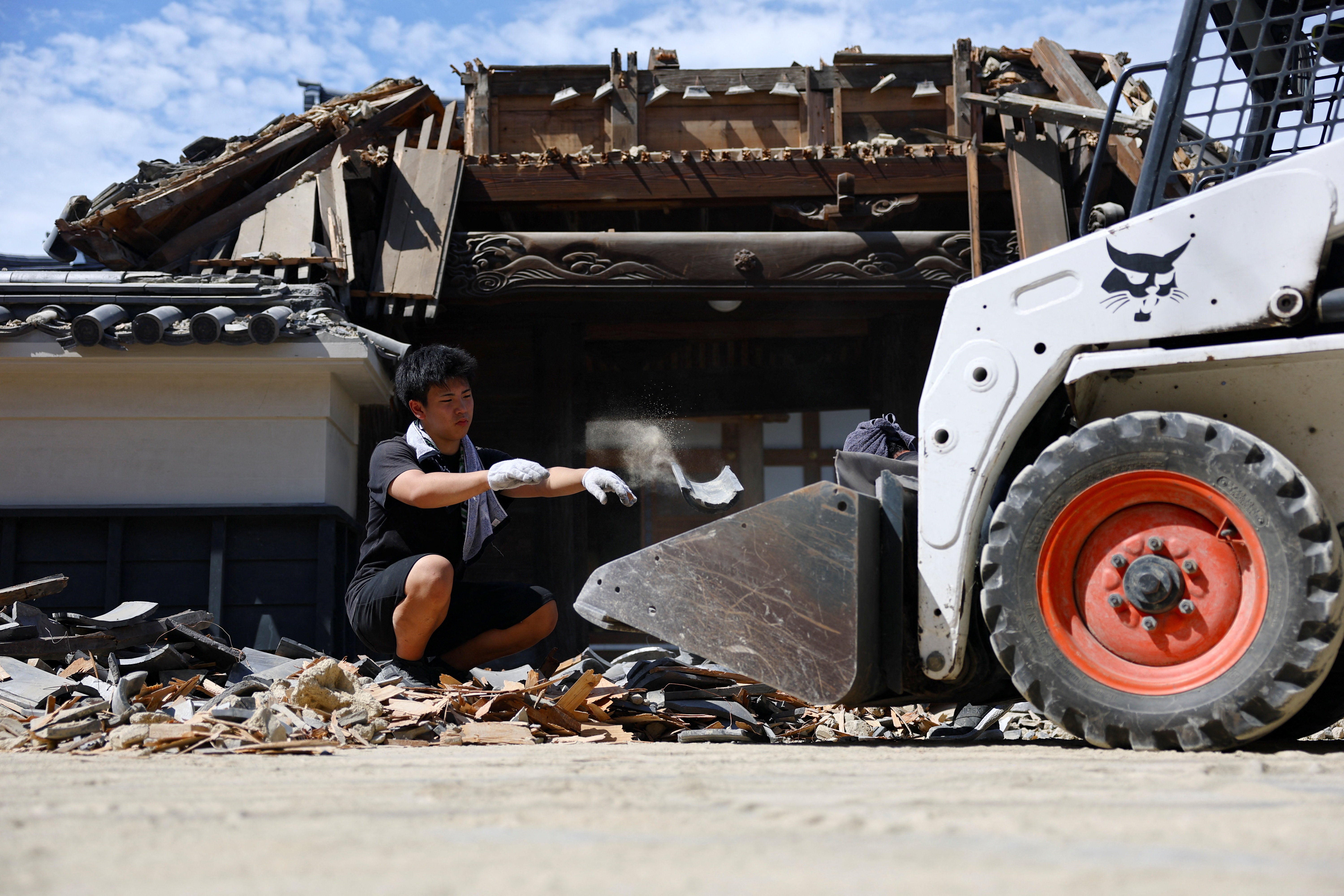 A person removes debris from a collapsed gate at a temple due to an earthquake (Reuters)