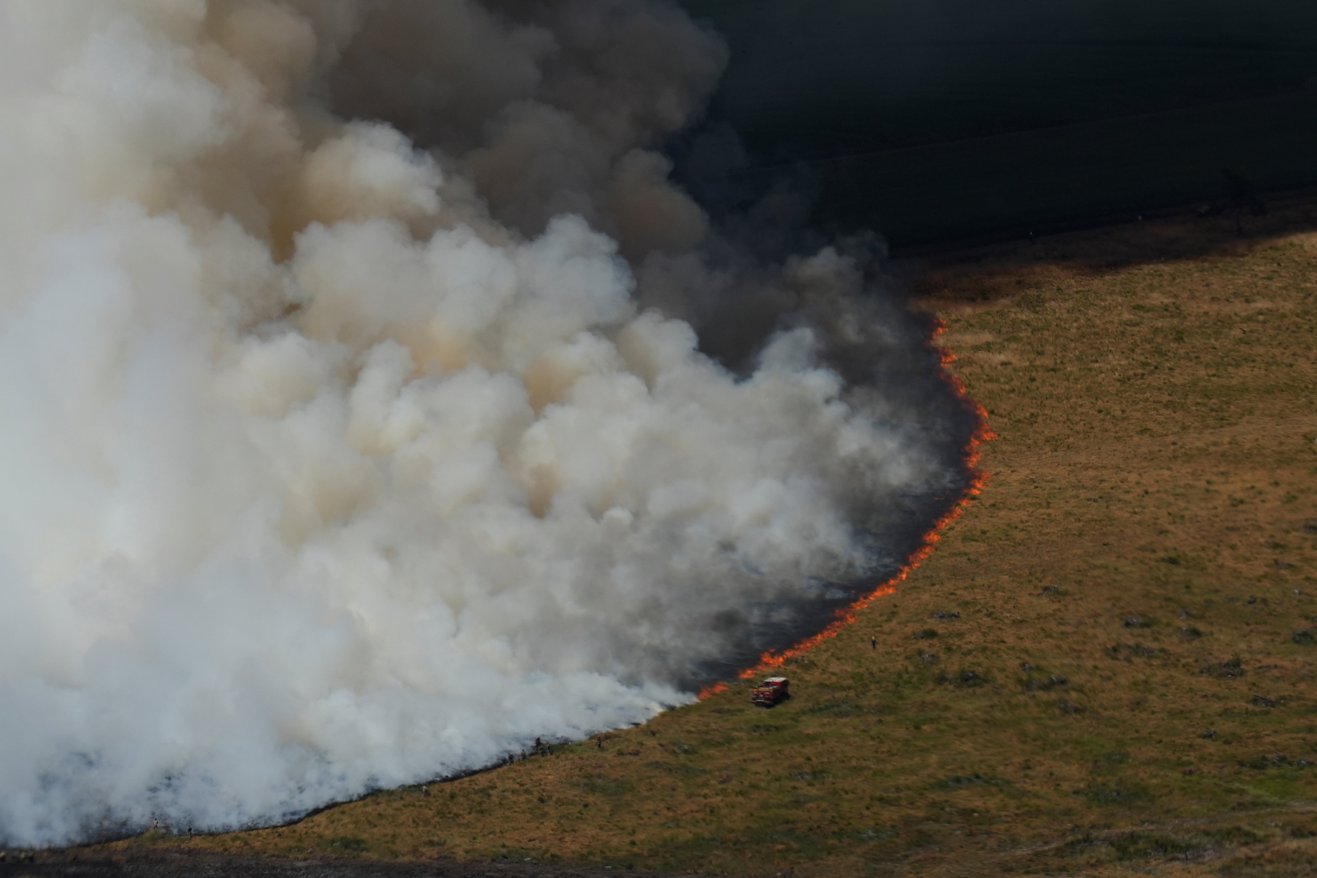 Firefighters work to suppress a blaze burning through a field near Ares, southwestern France