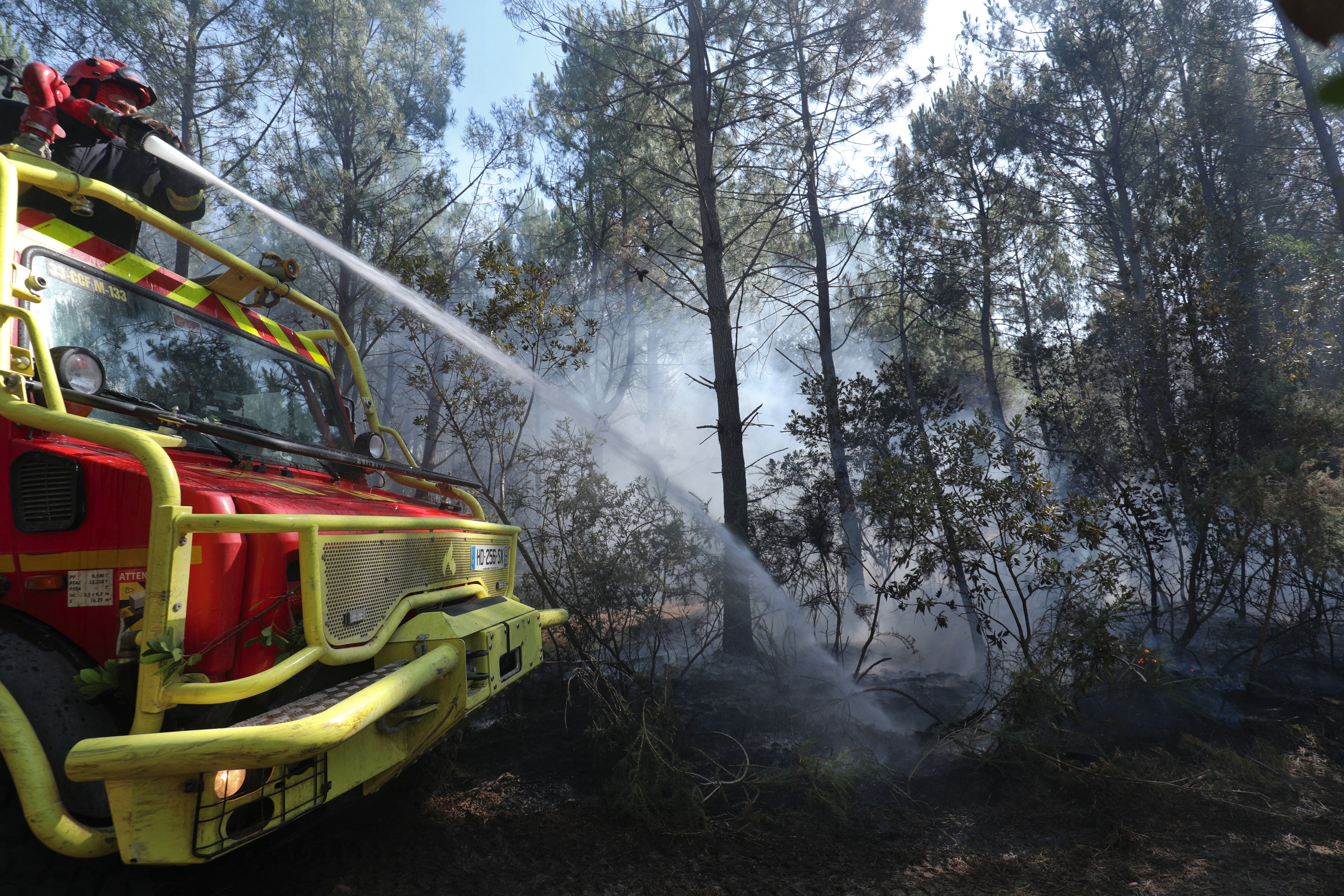 A French firefighter sprays water from the top of a fire engine to extinguish smoldering brush during ongoing forest fire suppression efforts in Lege-Cap-Ferret, southwestern France (AFP/Getty)