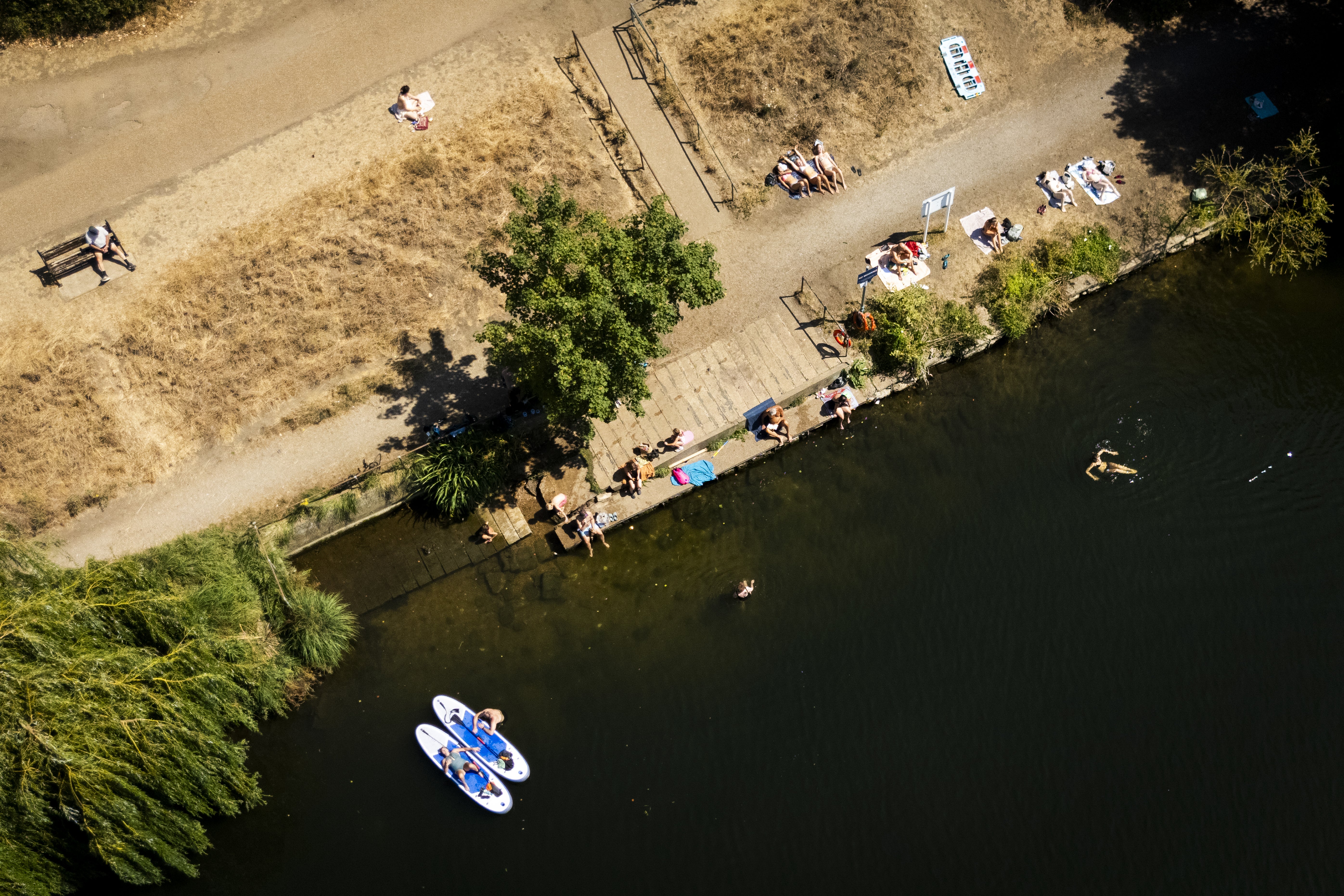 People sunbathing and swimming in the water at the Thames at Ham (PA)