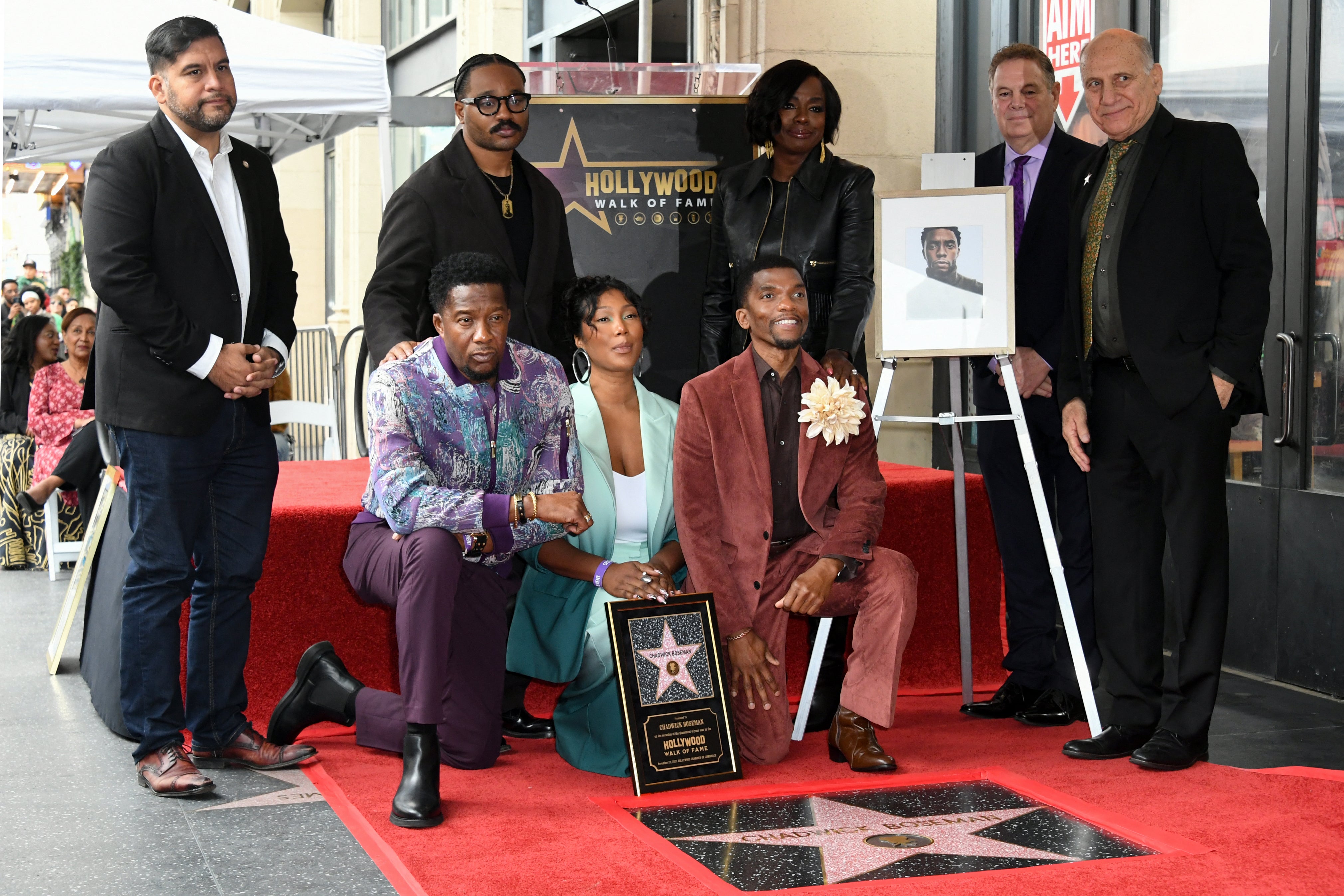 Chadwick Bosemans Witwe kniet zwischen zwei seiner Brüder vor seinem posthumen Stern auf dem Hollywood Walk of Fame