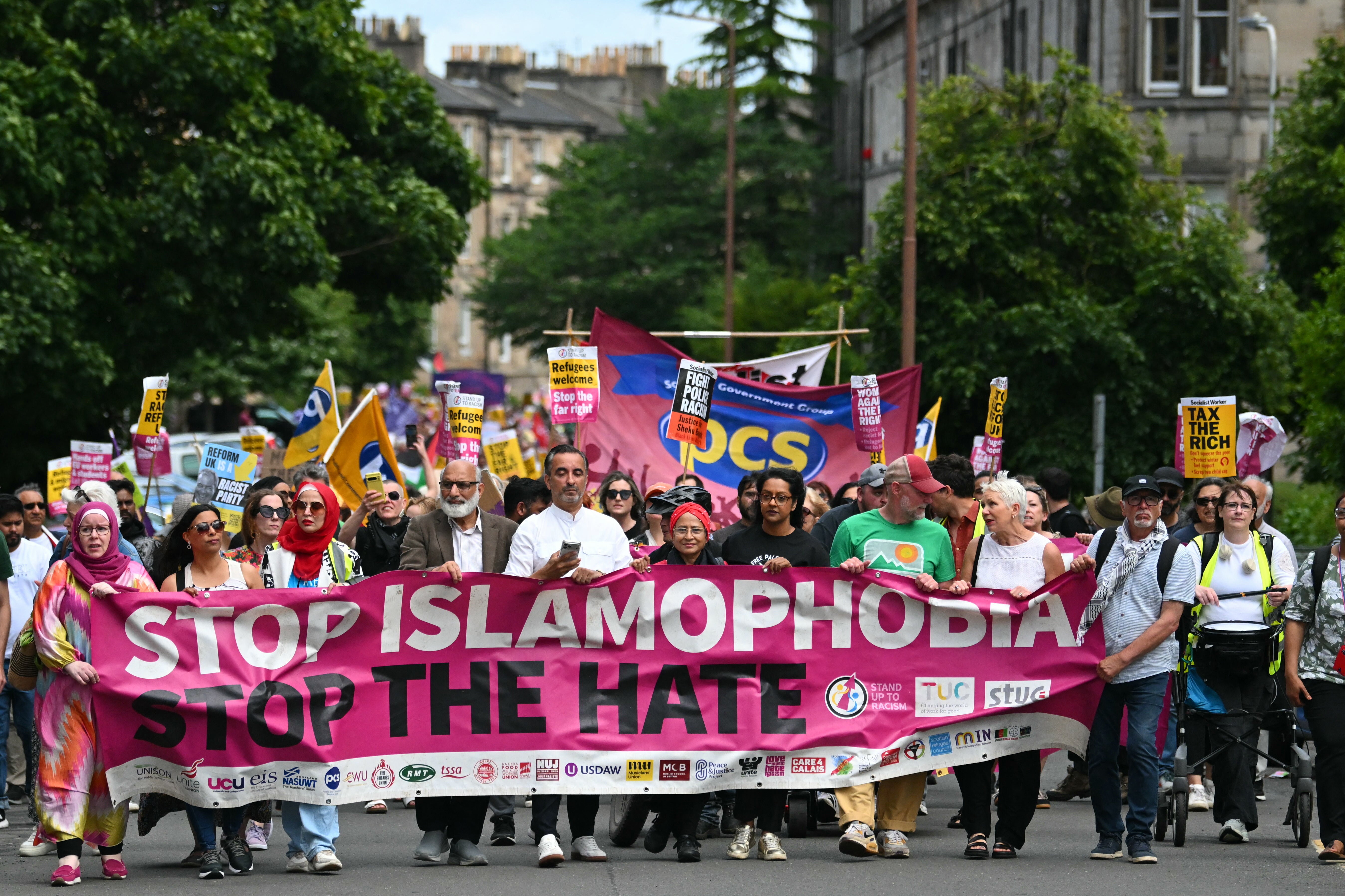 Aamer Anwar (C) and protesters display a banner as they take part in an anti-racism "Unity March and Rally", organised by Stand up to Racism, Scotland