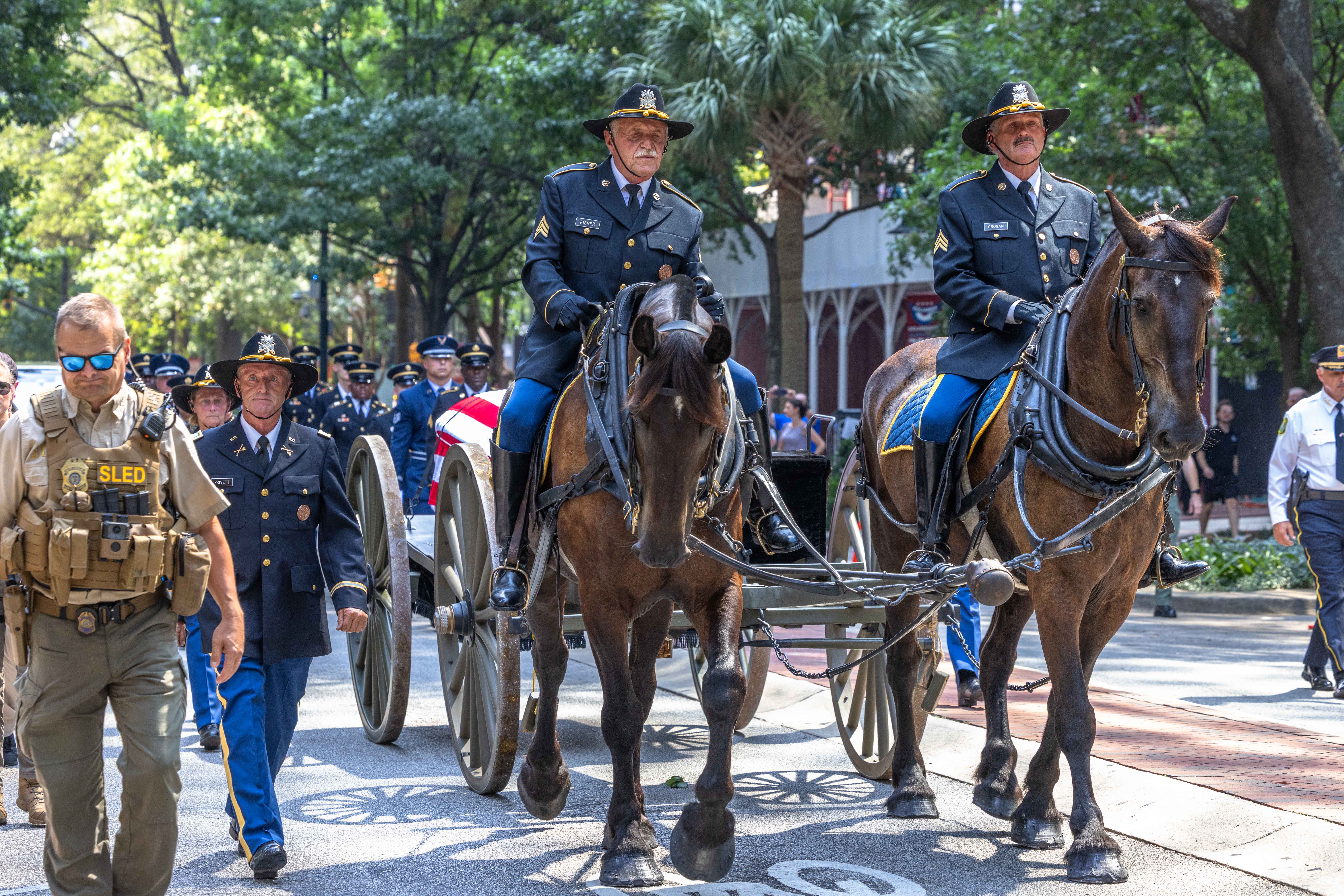 A horse-drawn caisson carrying his casket paused in front of a dozen law enforcement officers for a flyover by four military jets, and then proceeded to the church