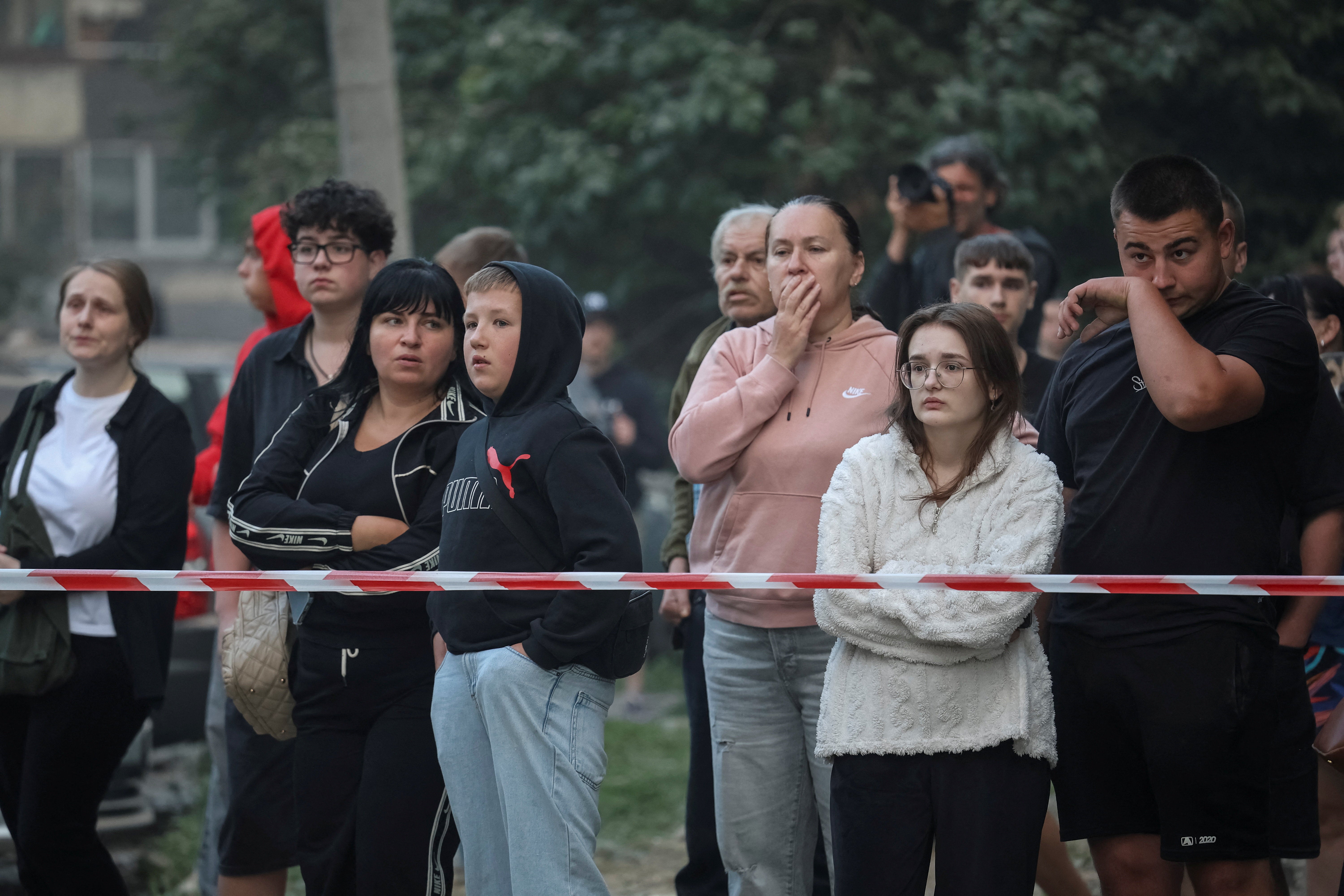 Residents stand at the site of an apartment building hit by a Russian missile strike, amid Russia's attack on Ukraine, in Lviv