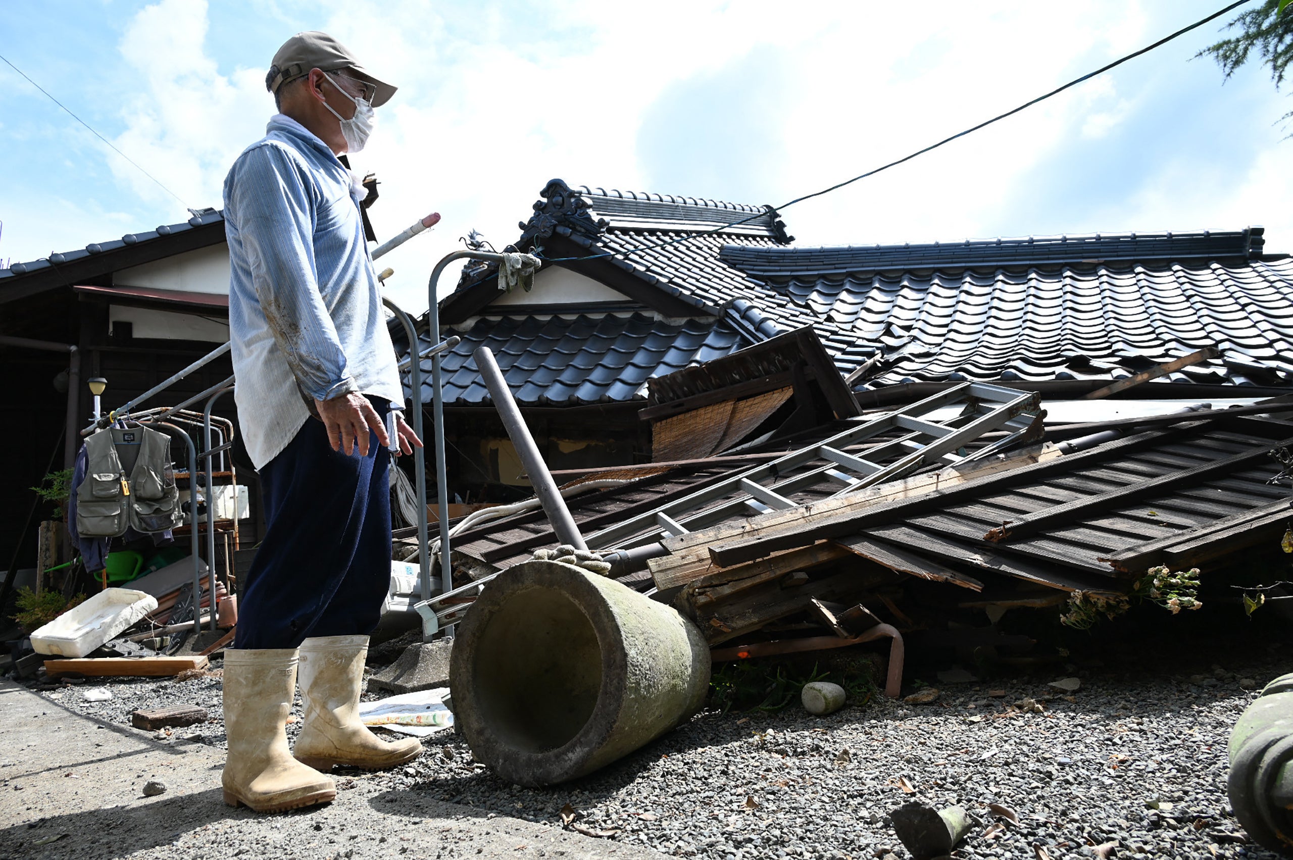 A man gazes at his collapsed home in Hikawa Town, Kumamoto Prefecture