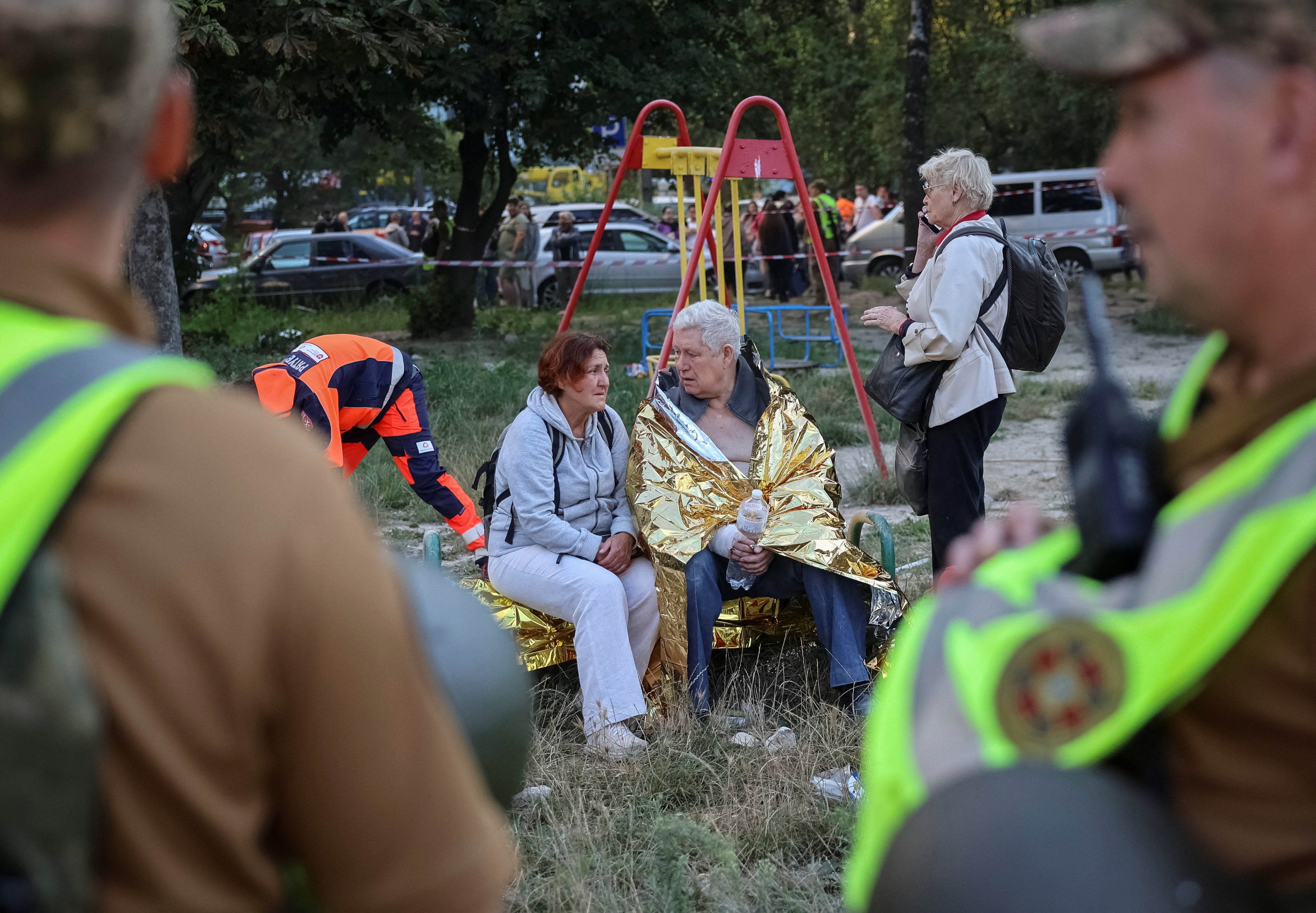 Residents sit at the site of an apartment building hit by a Russian missile strike