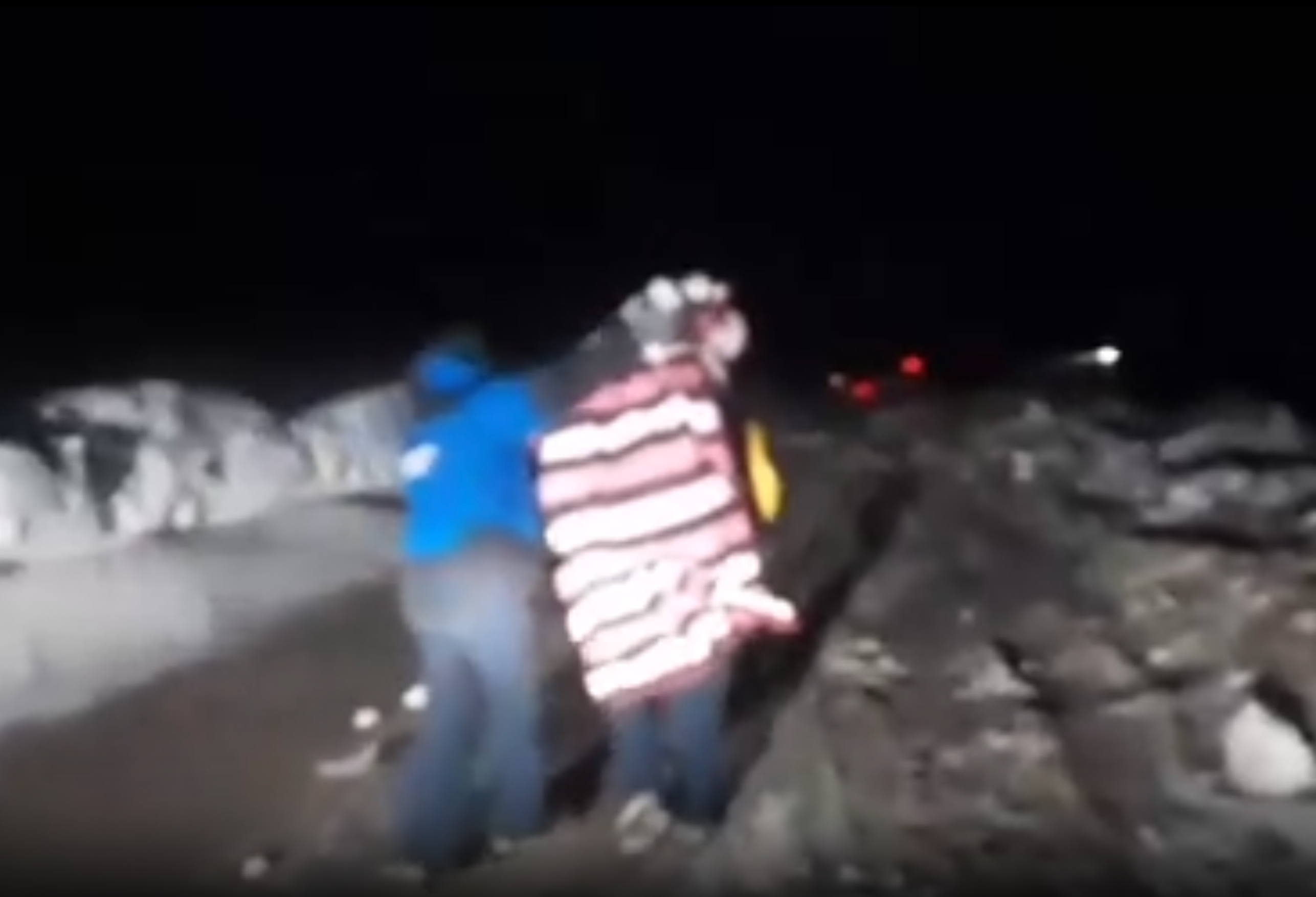 A tourist wrapped in blankets is rescued from their vehicle