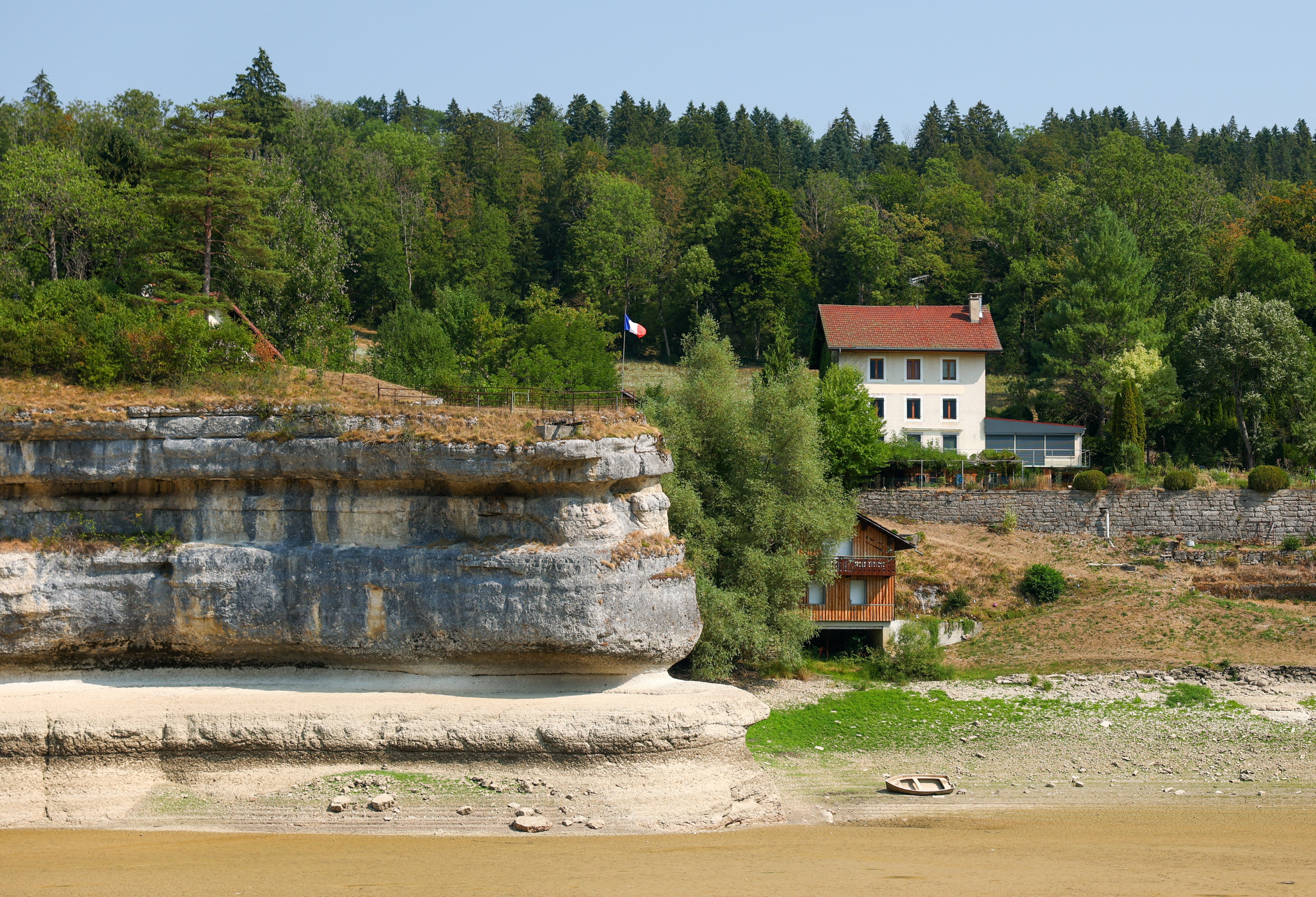 A French flag is pictured on a cliff at the nearly empty Lake Brenet, as drought conditions affecting the Doubs River lower water levels at the Swiss-French border in Les Brenets, Switzerland, July 30, 2026