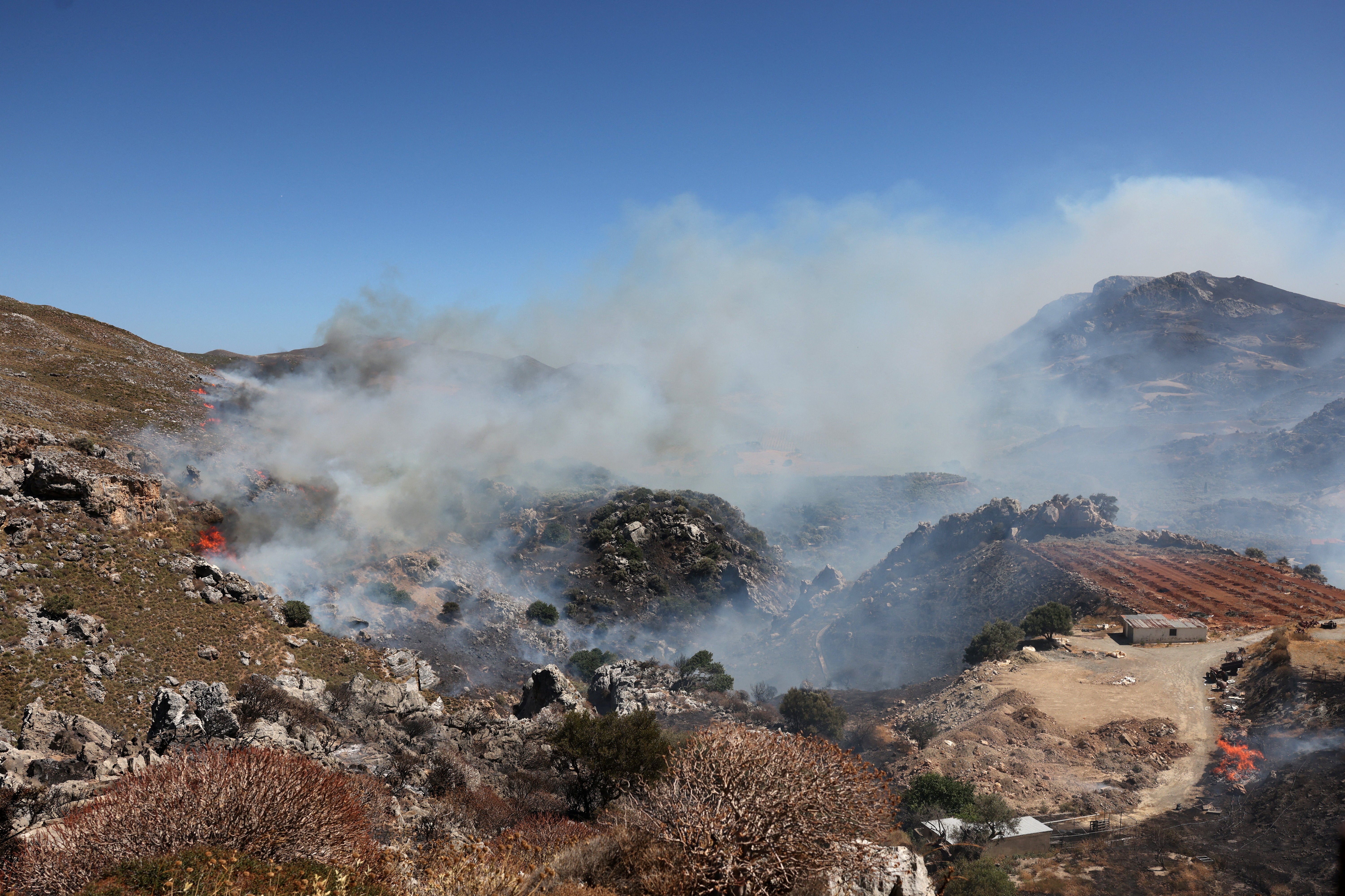 A wildfire burns in a canyon near Asomatos village on the island of Crete, Greece (Reuters)