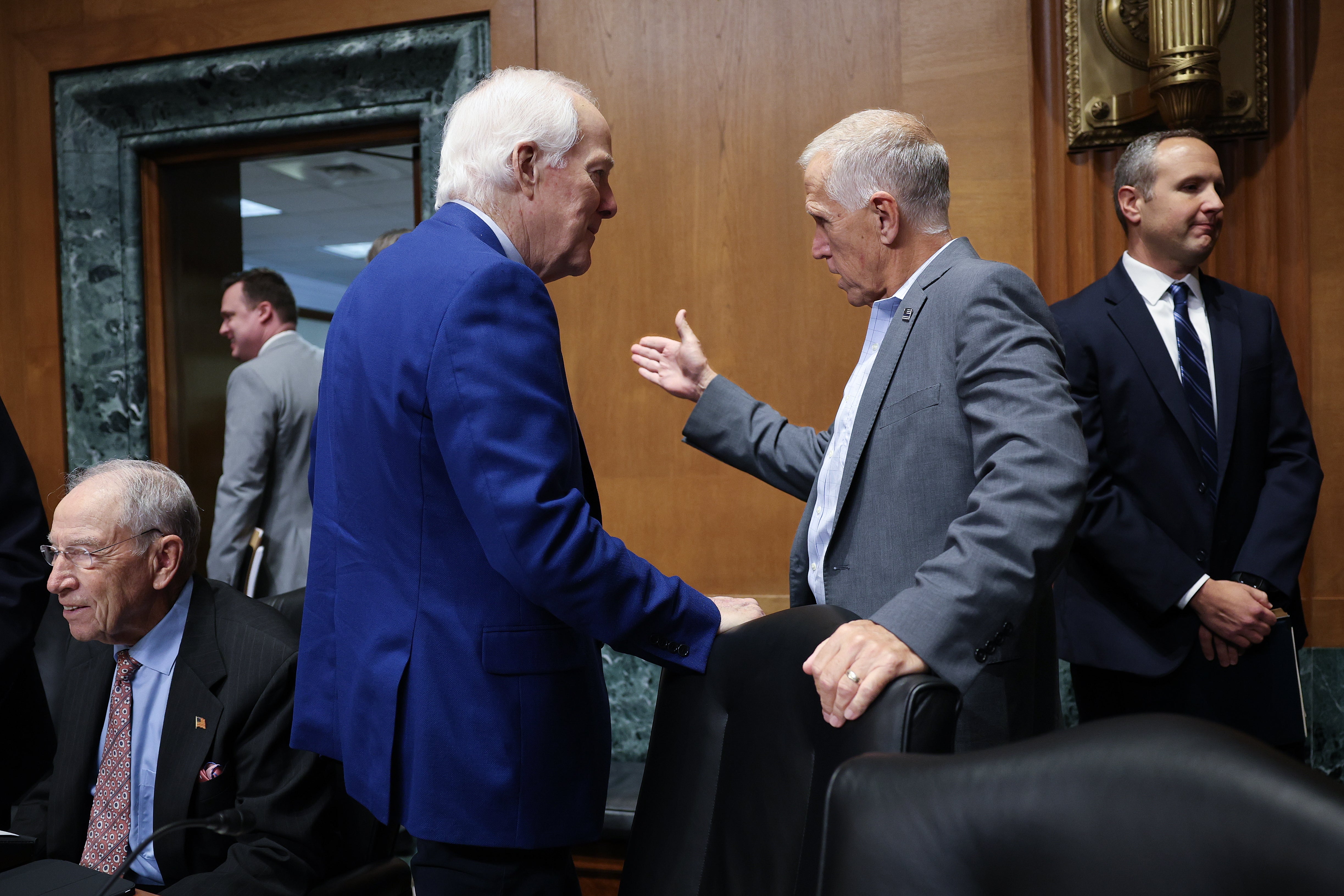 Sen. John Cornyn (R-TX) (at left) talks with Sen. Thom Tillis (R-NC) during a Senate Finance Committee hearing Thursday. Both are withholding support for President Donald Trump's nominee for U.S. attorney general, Todd Blanche, until they get reassurances on Trump’s IRS lawsuit settlement and the elimination of the ‘anti-weaponization fund.’ (Getty)