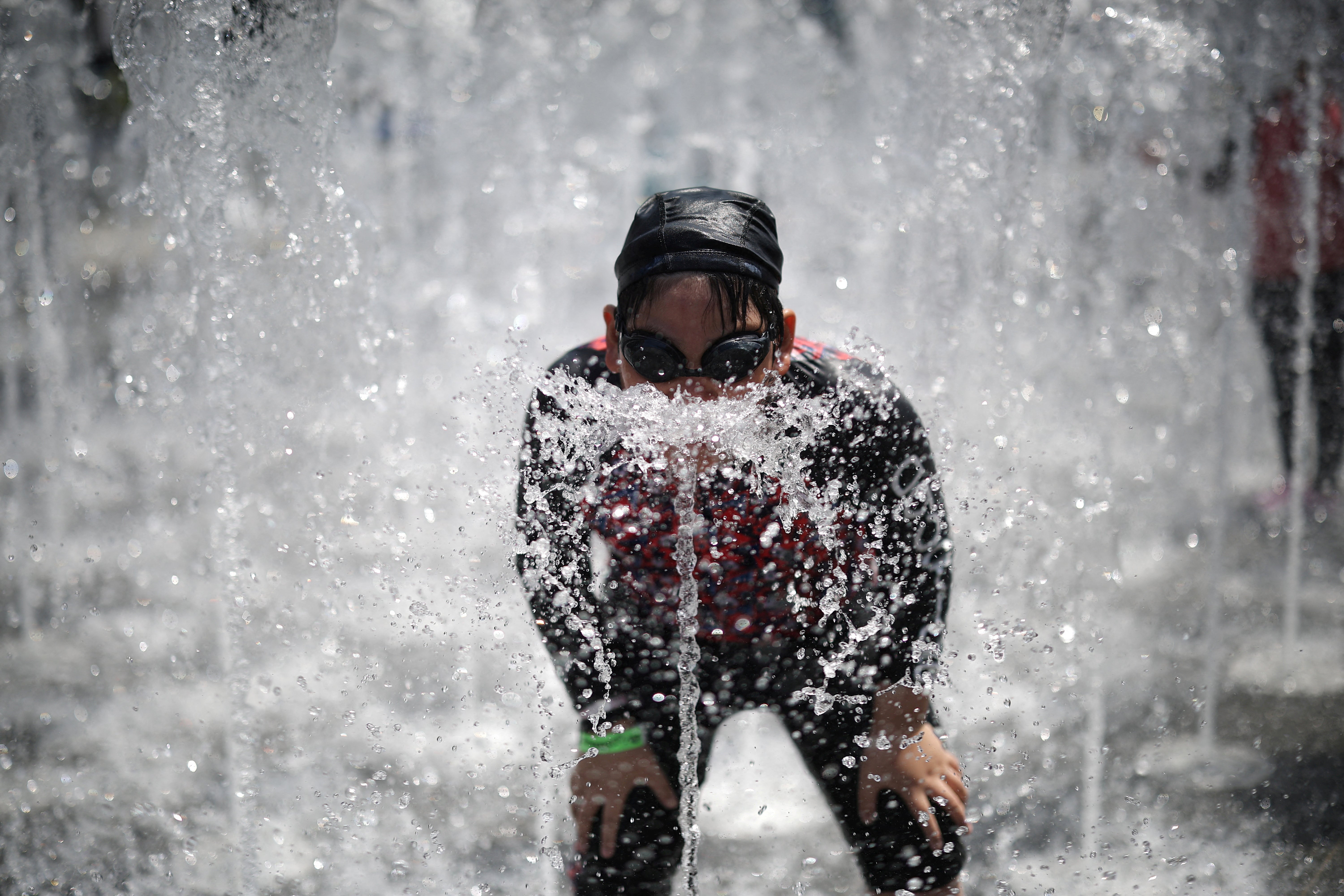 A boy plays at a ground fountain during a heatwave in central Seoul, South Korea (Reuters)