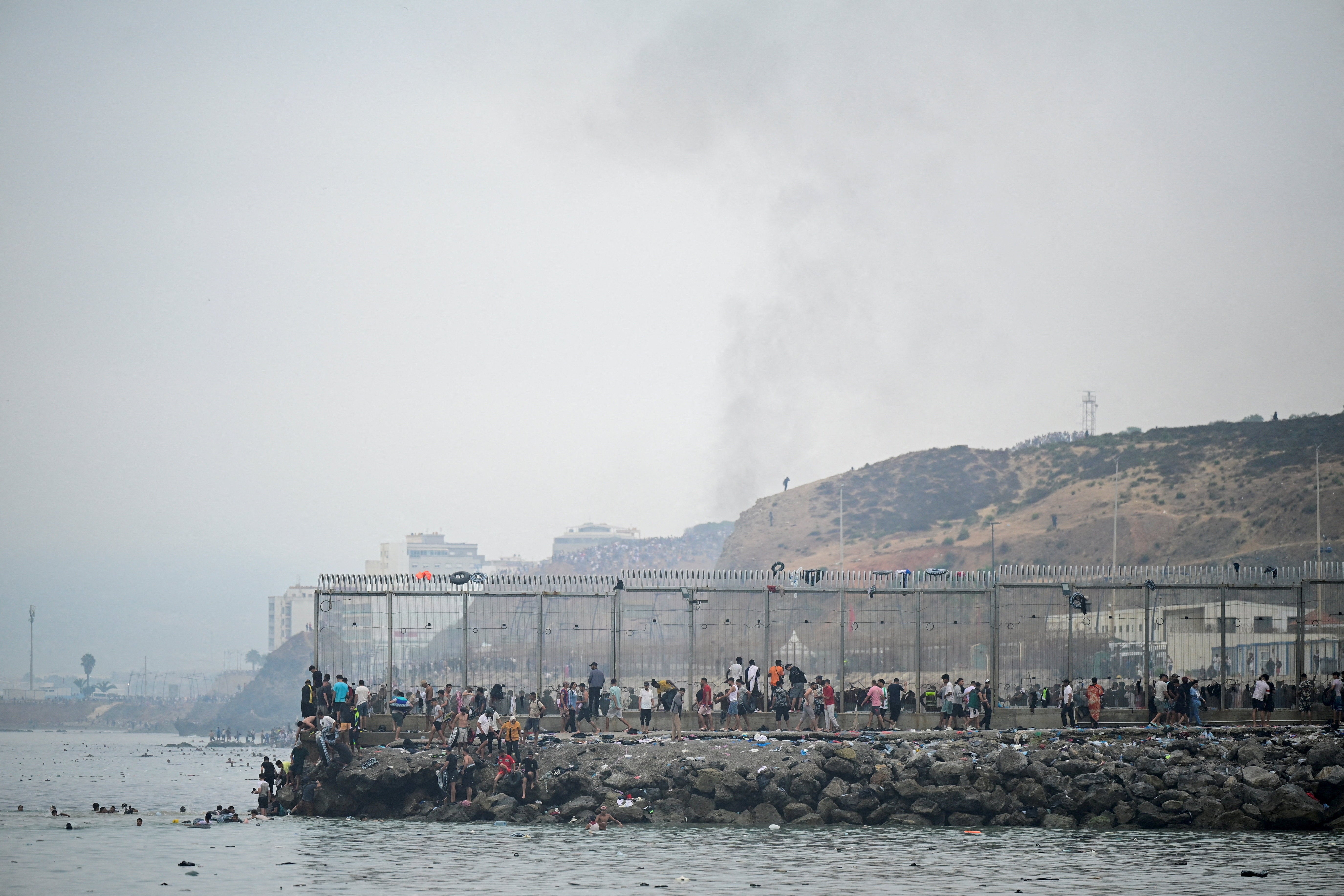 Migrants from Morocco gather by the border fence as they cross the Spanish border, swimming through the sea, as seen from Ceuta, Spain, July 31, 2026. (REUTERS/Fabian Bimmer) (Reuters)