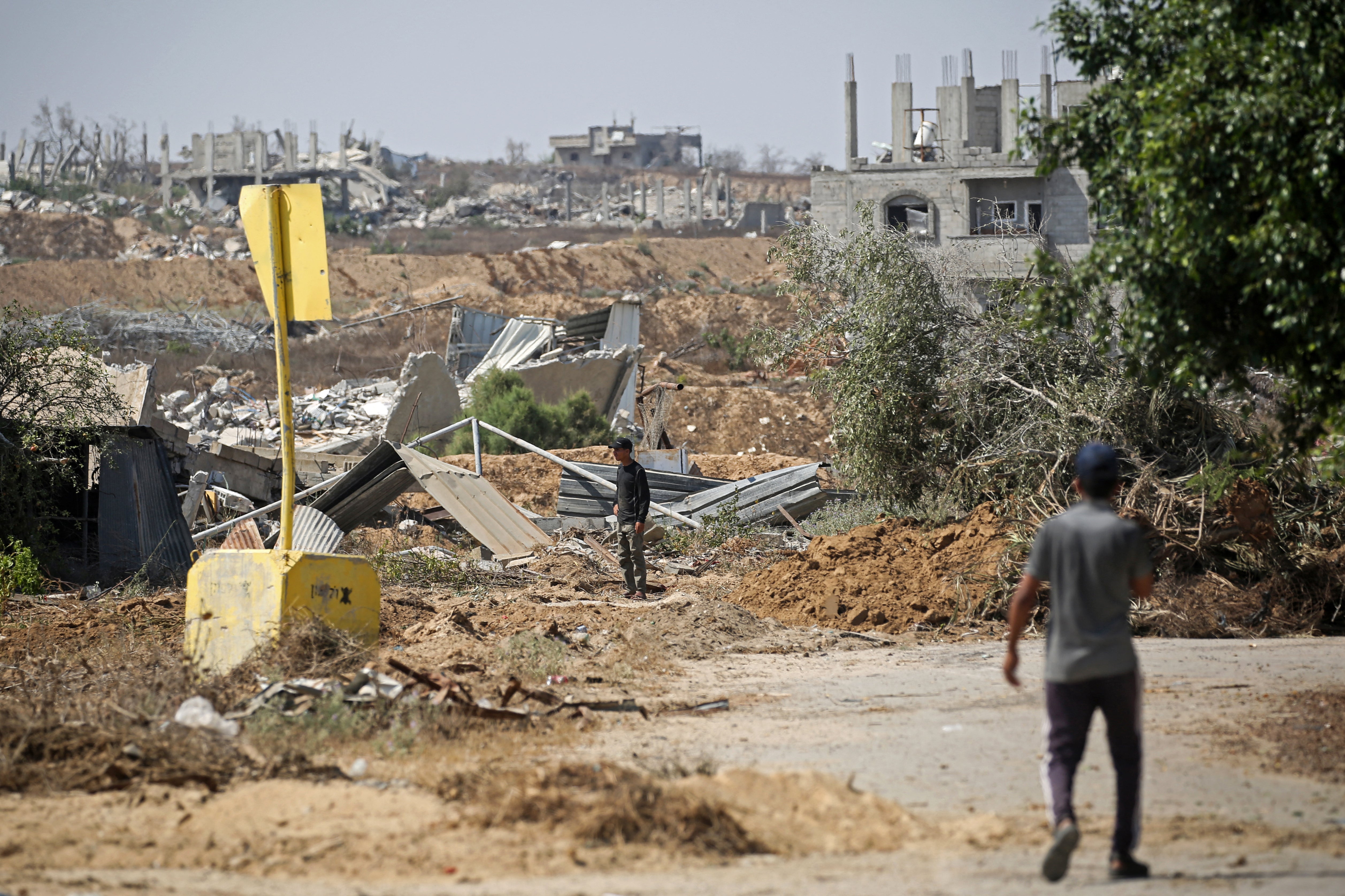 Palestinians walk past a concrete block marking the 'Yellow Line' drawn by the Israeli military in the east of Deir al-Balah, central Gaza Strip