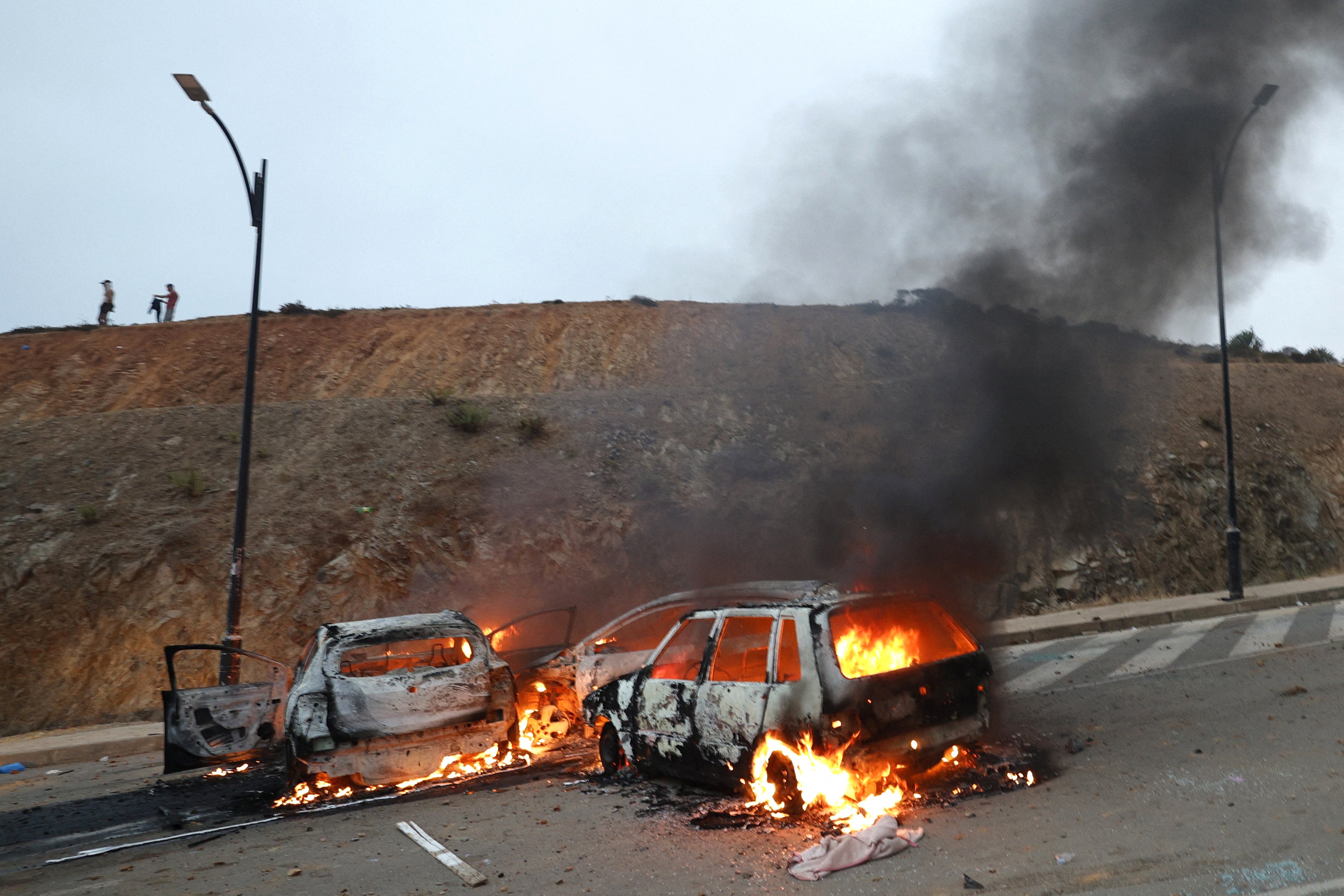 Vehicles burn at the site of clashes near Fnideq, on the Morocco-Spain border