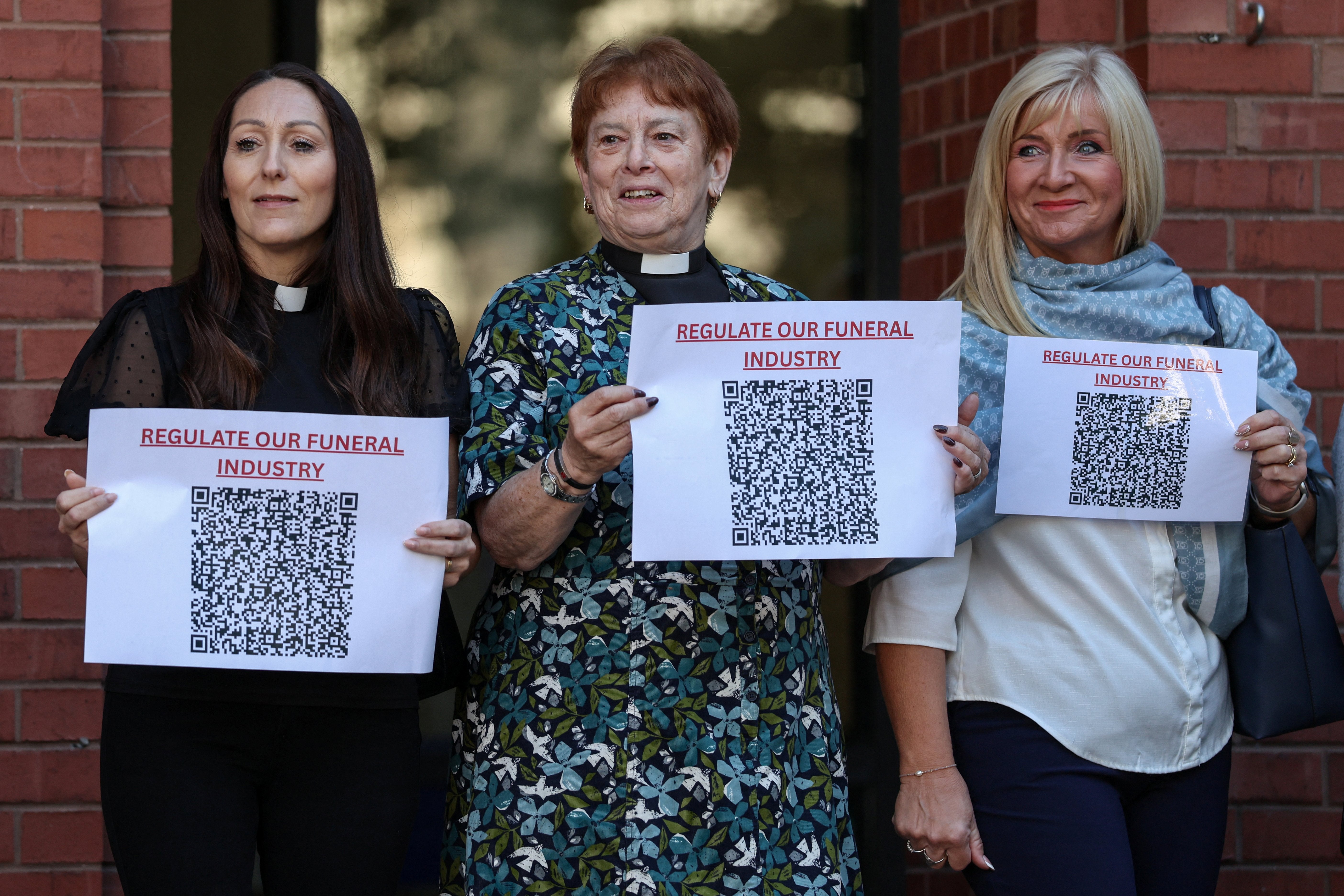 People hold signs calling for the regulation of the funeral industry, outside the Hull Crown Court in the Lowgate area of Kingston upon Hull on July 27, 2026 (AFP/Getty)