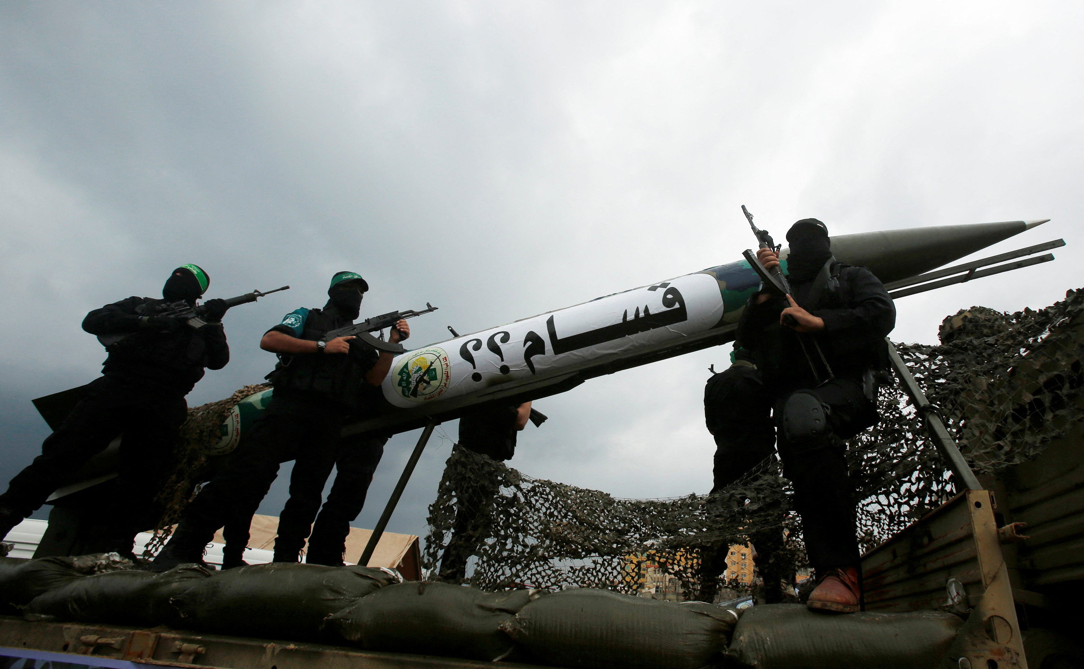 Palestinian members of al-Qassam Brigades, the armed wing of the Hamas movement, display a home-made Qassam rocket