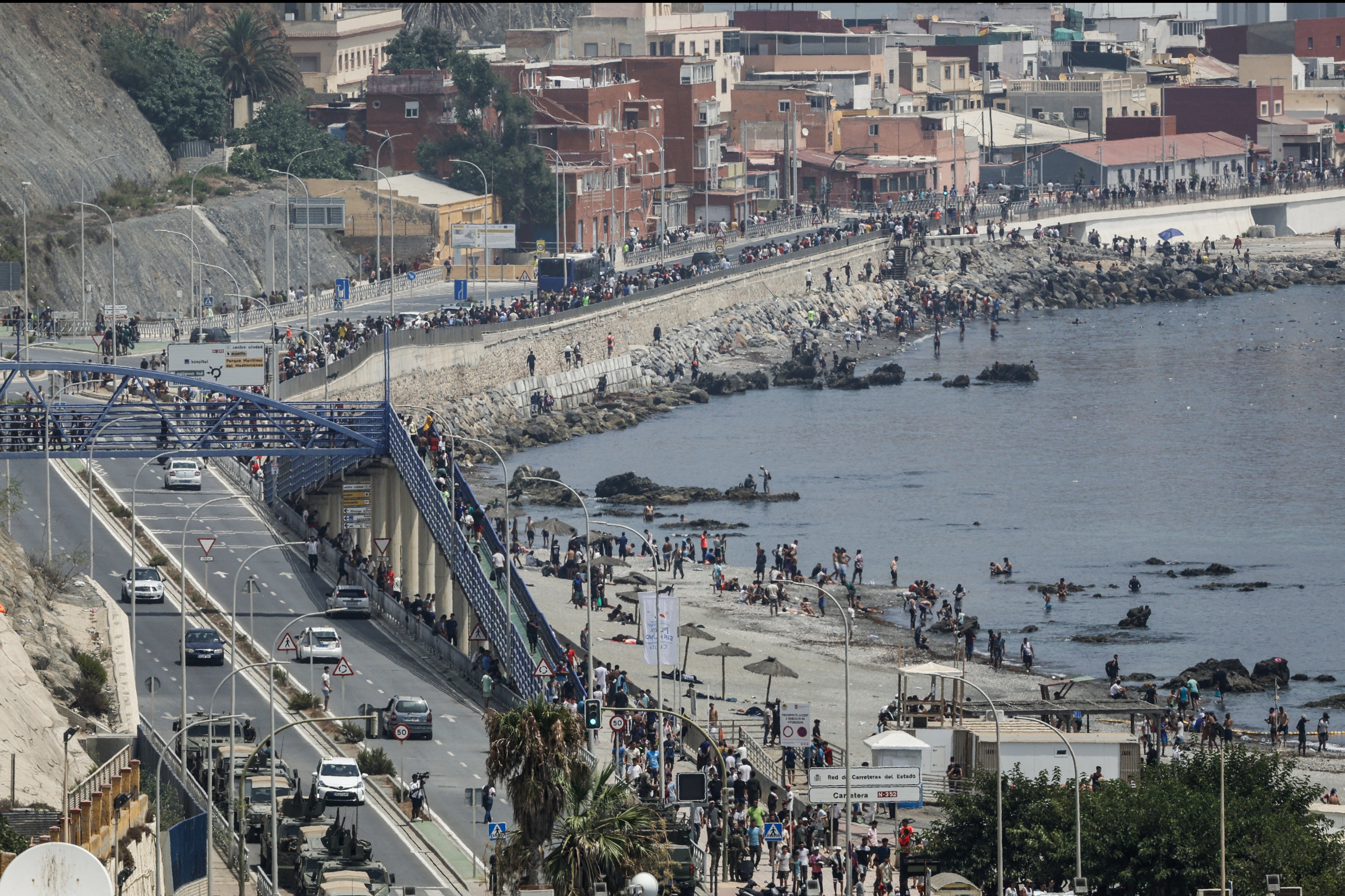 A photograph taken from the outskirts of the Moroccan town of Fnideq on the Morocco-Spain border shows migrants walking along the coast of Ceuta (Photo by Abdel Majid BZIOUAT / AFP via Getty Images) (AFP/Getty)