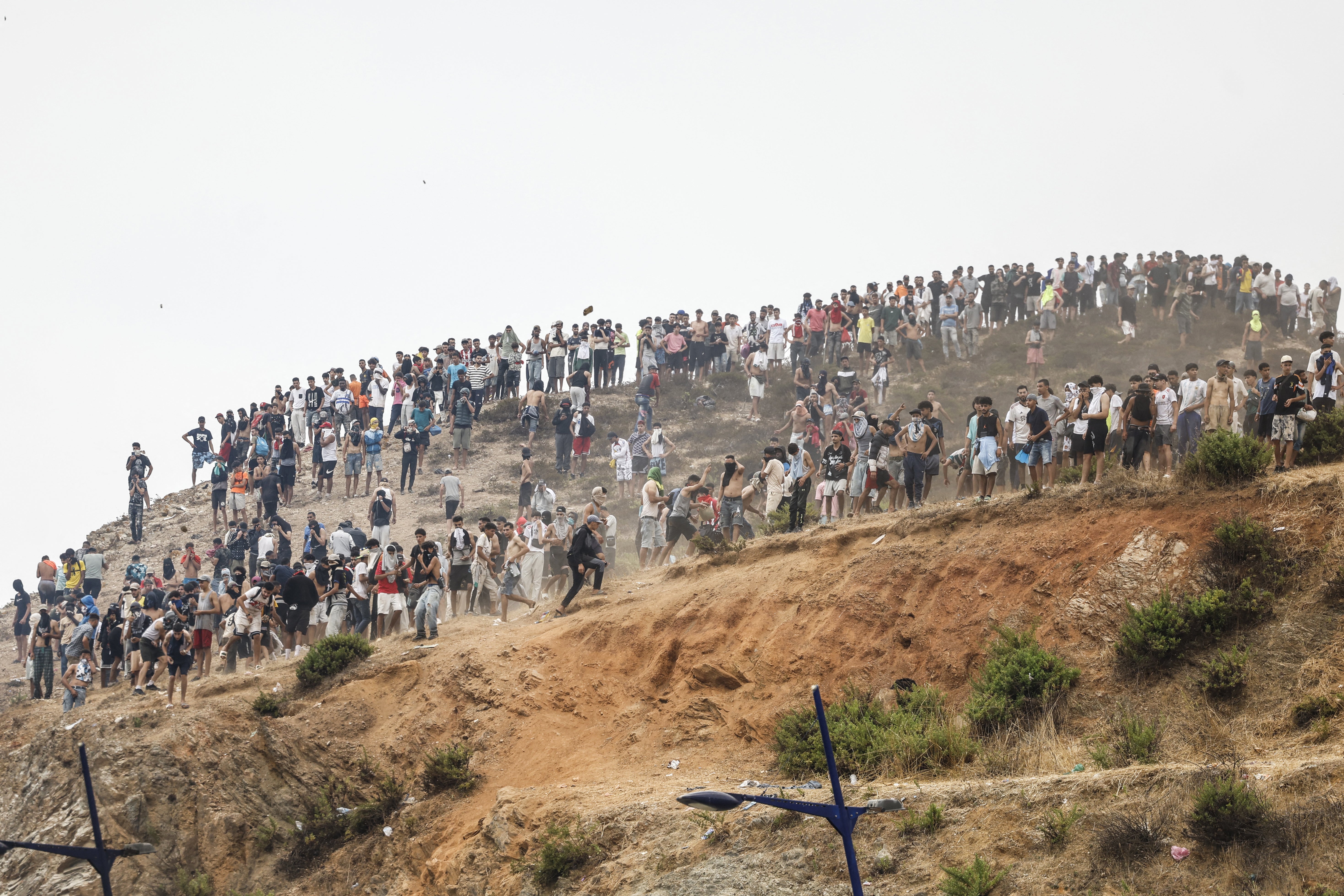 Migrants attempting to cross into Spain's North African enclave of Ceuta gather on a hilltop during clashes with Moroccan security forces