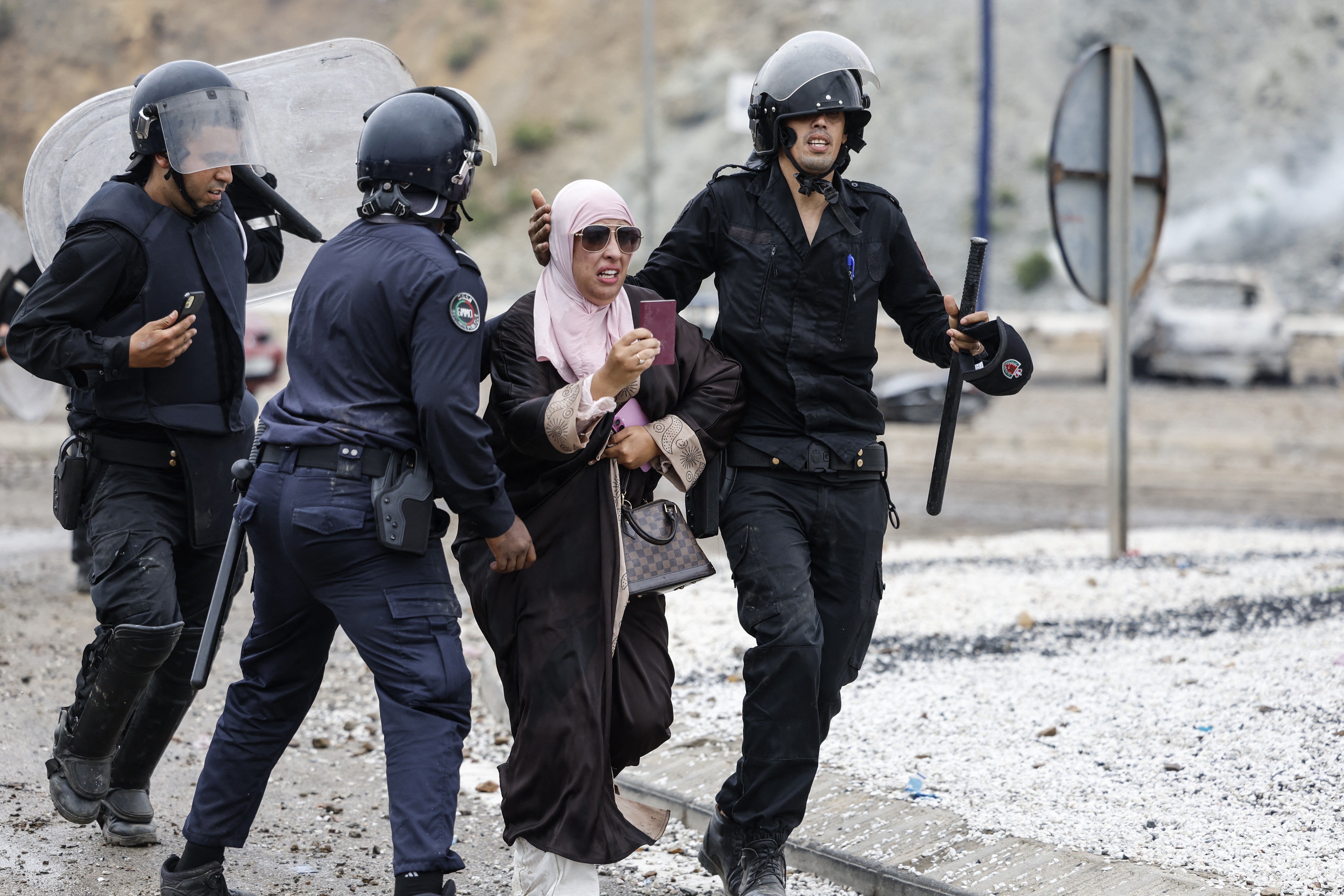 A woman is escorted by Moroccan security forces during clashes with migrants attempting to cross into Spain's North African enclave of Ceuta near the town of Fnideq, on the Morocco-Spain borde (AFP/Getty)