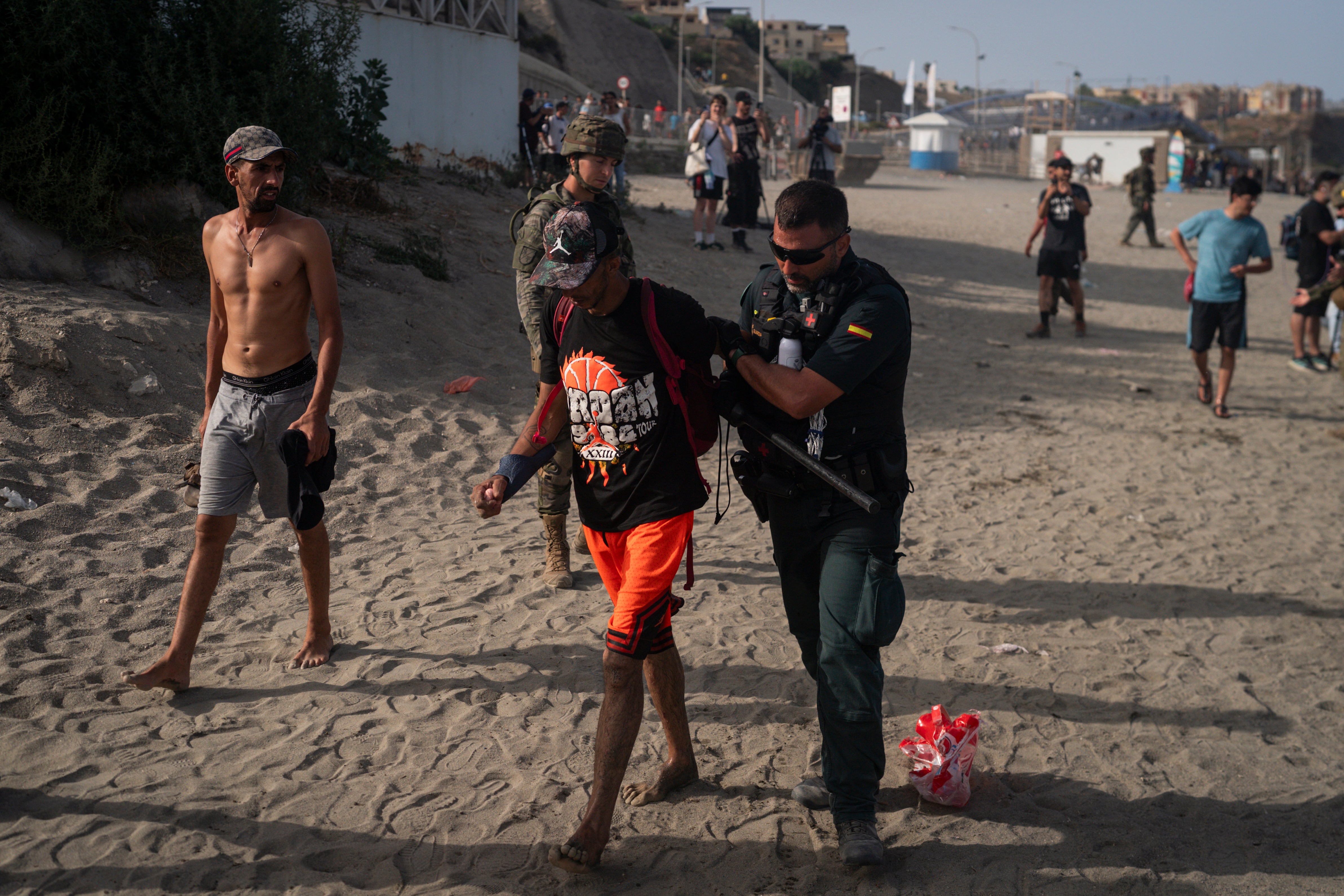 A member of the Guardia Civil USECIC restrains a migrant after arriving on Tarajal beach after crossing the border between Spain and Morocco (Getty)