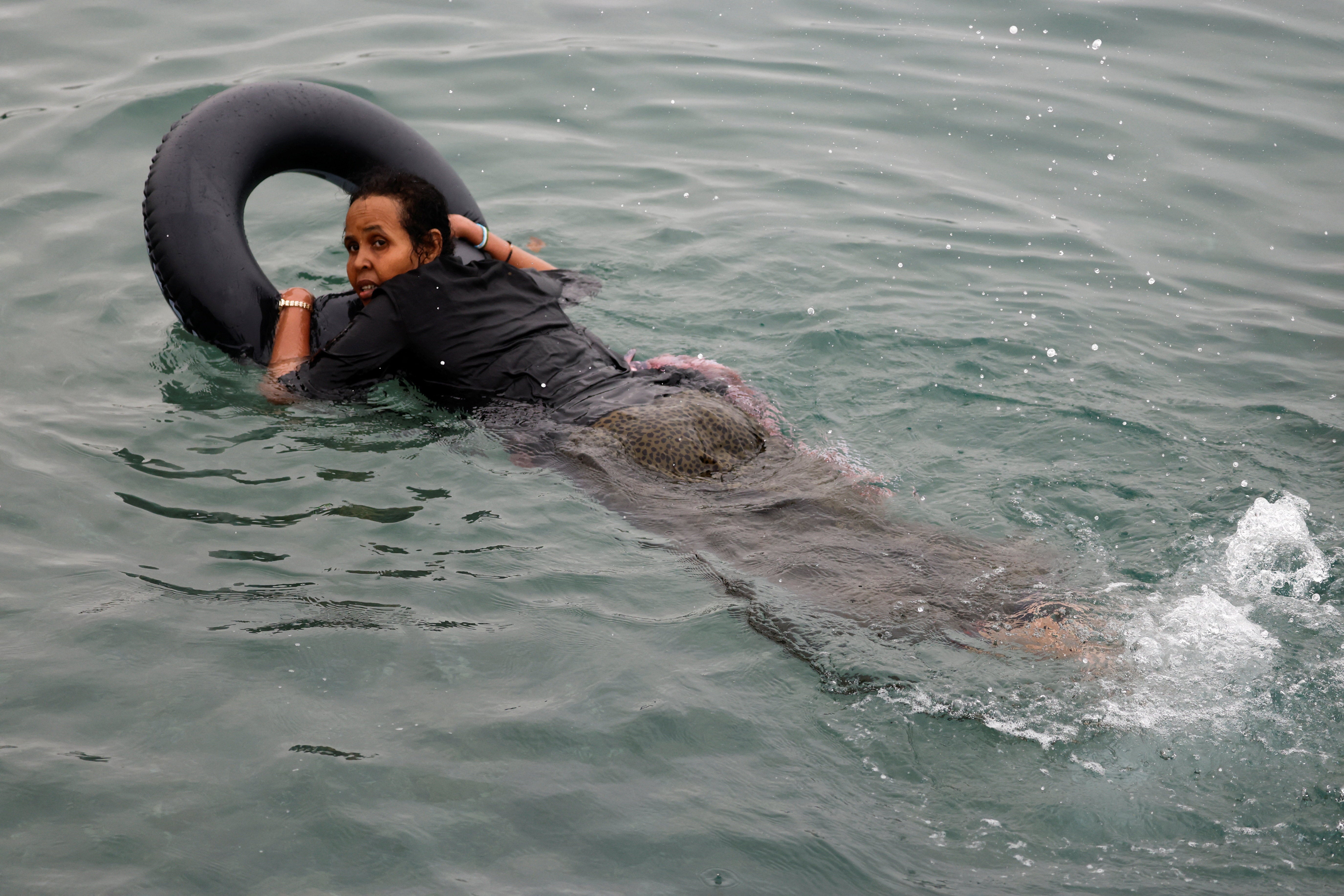 Filiss, 32, from Somalia uses a float to cross into Ceuta by sea, at El Tarajal beach, amid mass crossings of migrants from Morocco into Spanish territory