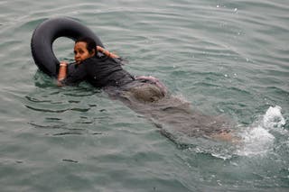 Filiss, 32, from Somalia uses a float to cross into Ceuta by sea, at El Tarajal beach, amid mass crossings of migrants from Morocco into Spanish territory