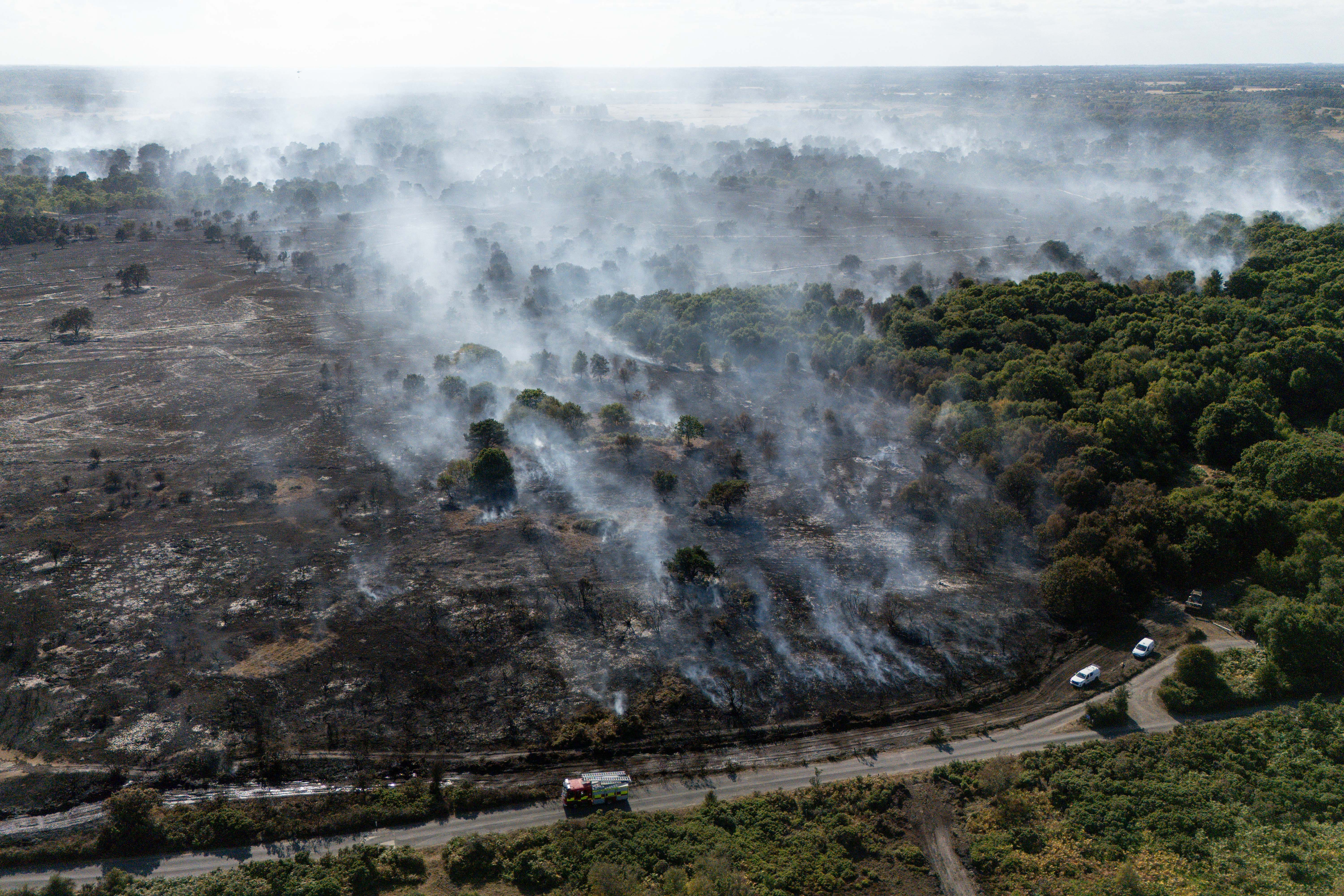 Smoke rises from the smouldering remains of a wildfire at Dunwich Heath (PA Wire)