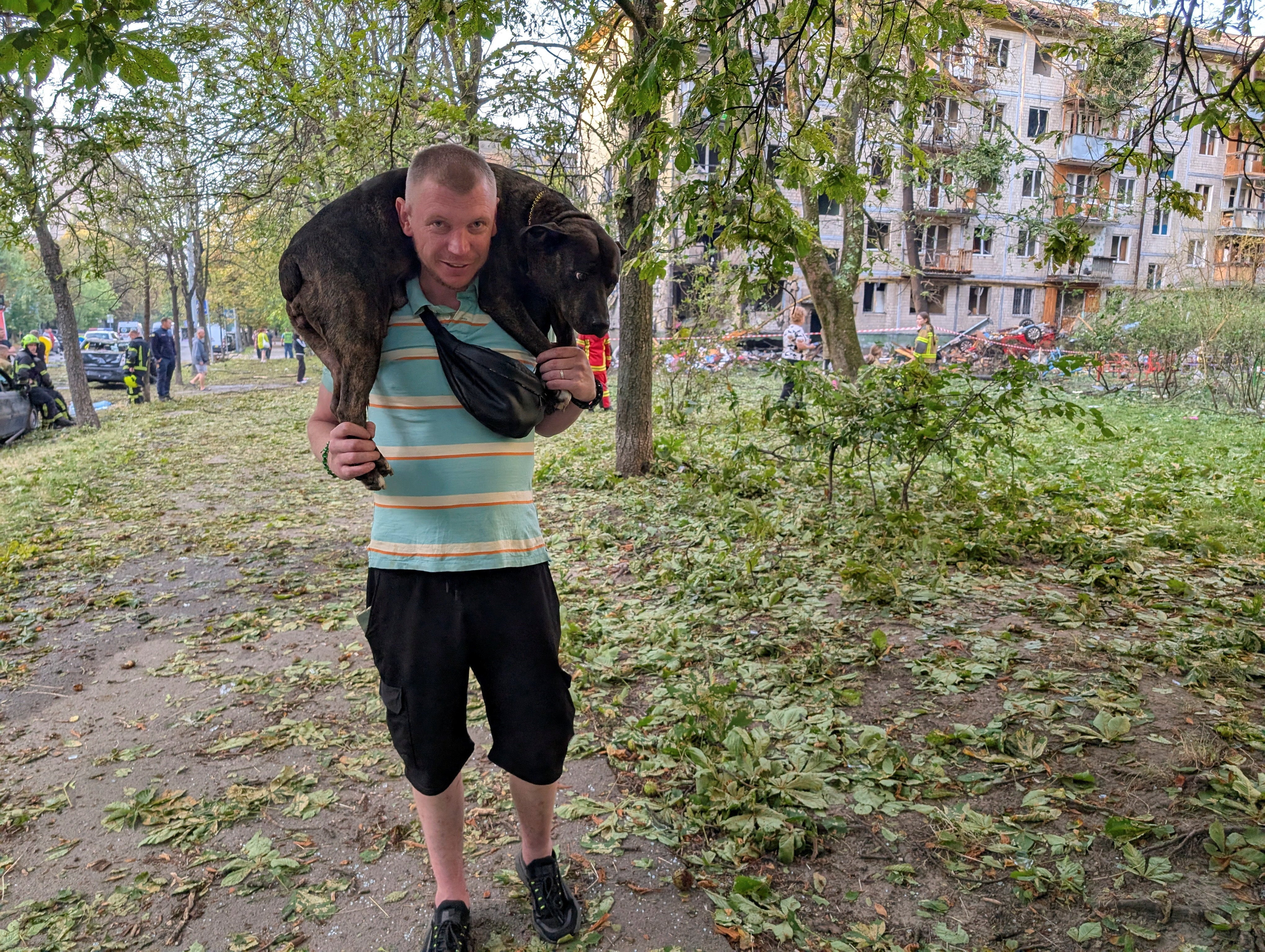 A man carries his dog at the site of an apartment building hit by a Russian missile strike, amid Russia's attack on Ukraine, in Kyiv, Ukraine (Reuters)