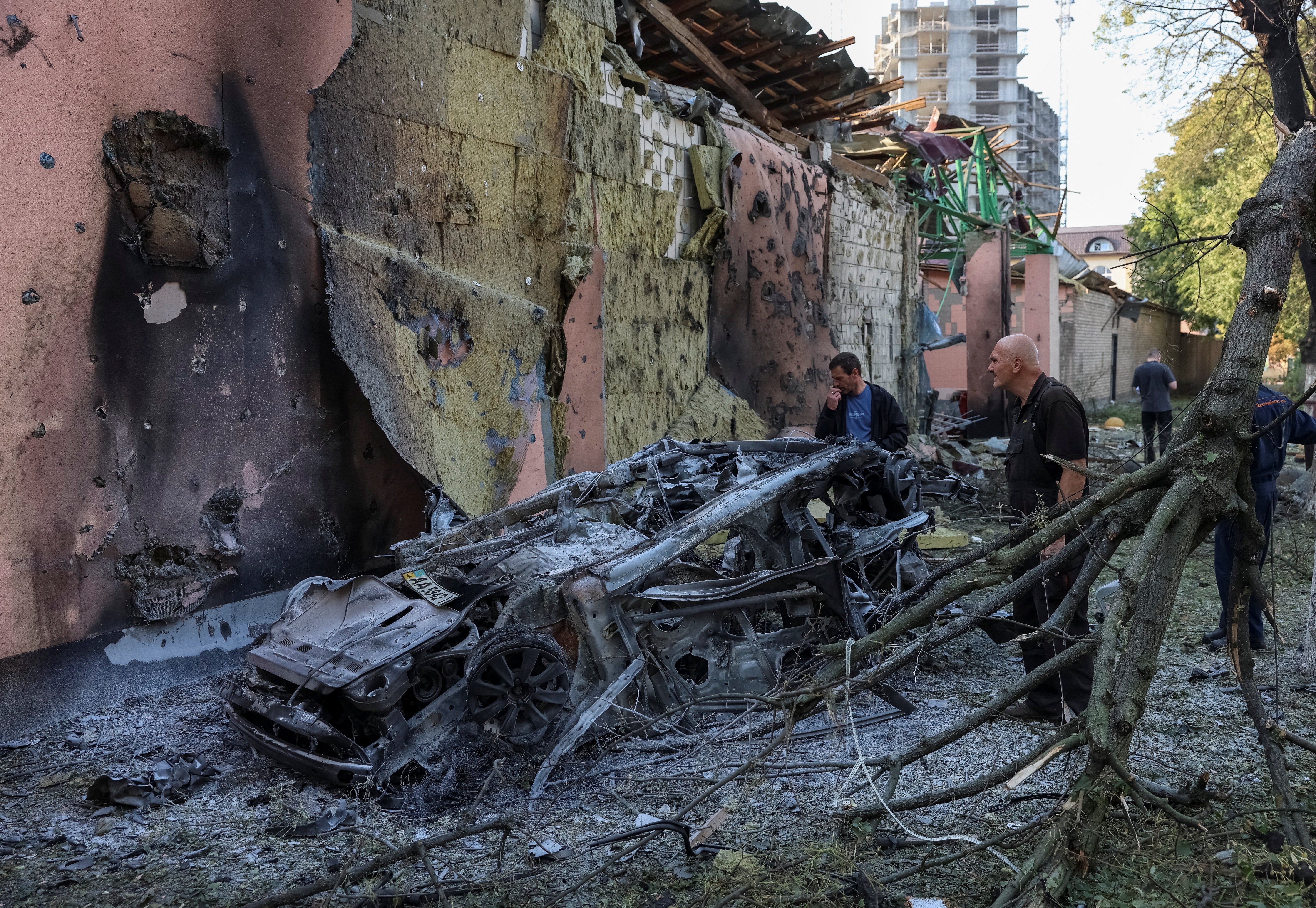 Residents look at a burned car at a site of a Russian missile strike, amid Russia's attack on Ukraine, in Kyiv region, Ukraine (Reuters)