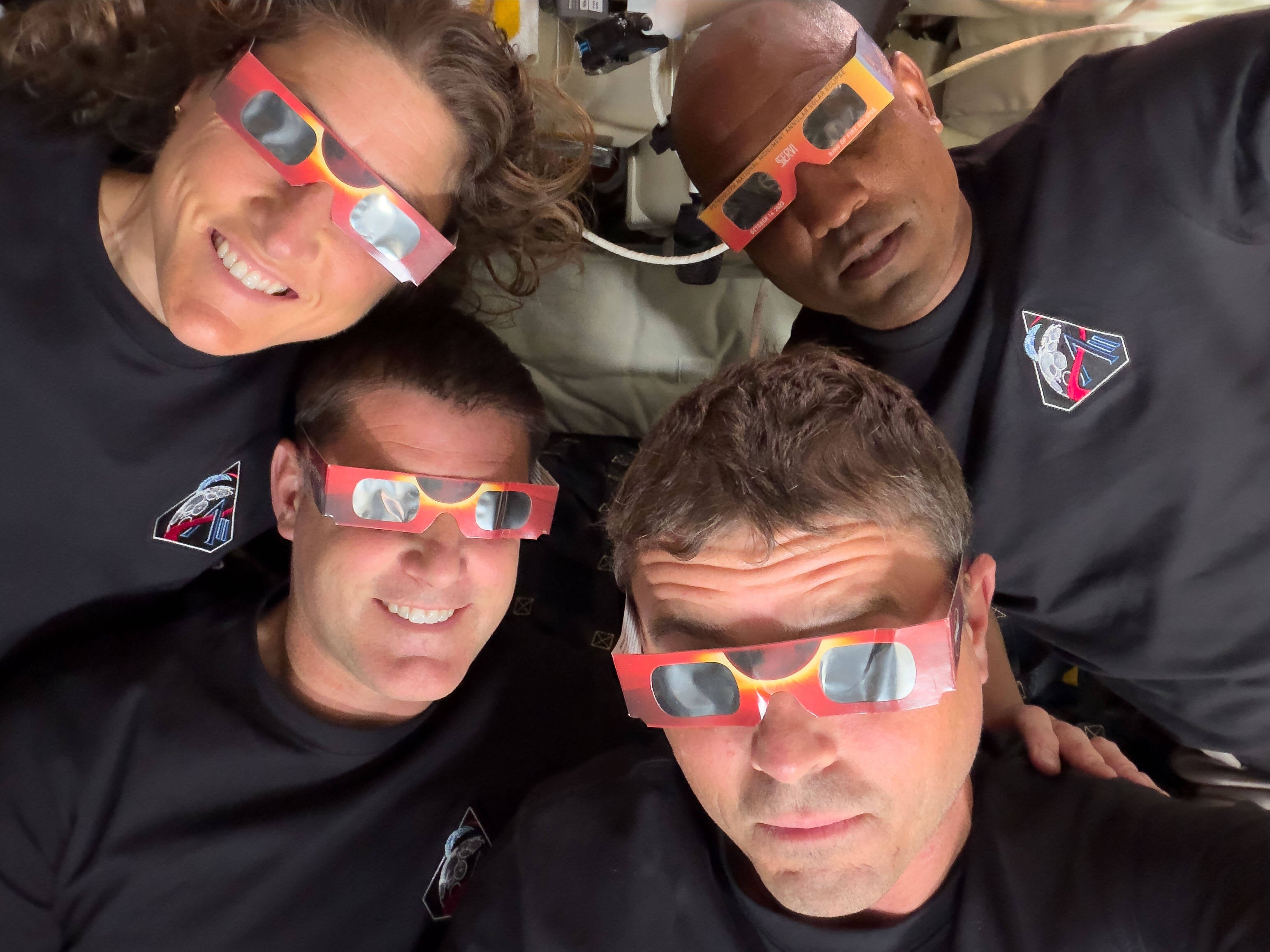 In this image provided by NASA the Artemis II crew, counterclockwise from top left, Mission Specialist Christina Koch, Mission Specialist Jeremy Hansen, Commander Reid Wiseman and Pilot Victor Glover pose with eclipse viewers during a lunar flyby on April 6, 2026. (NASA via AP, File)